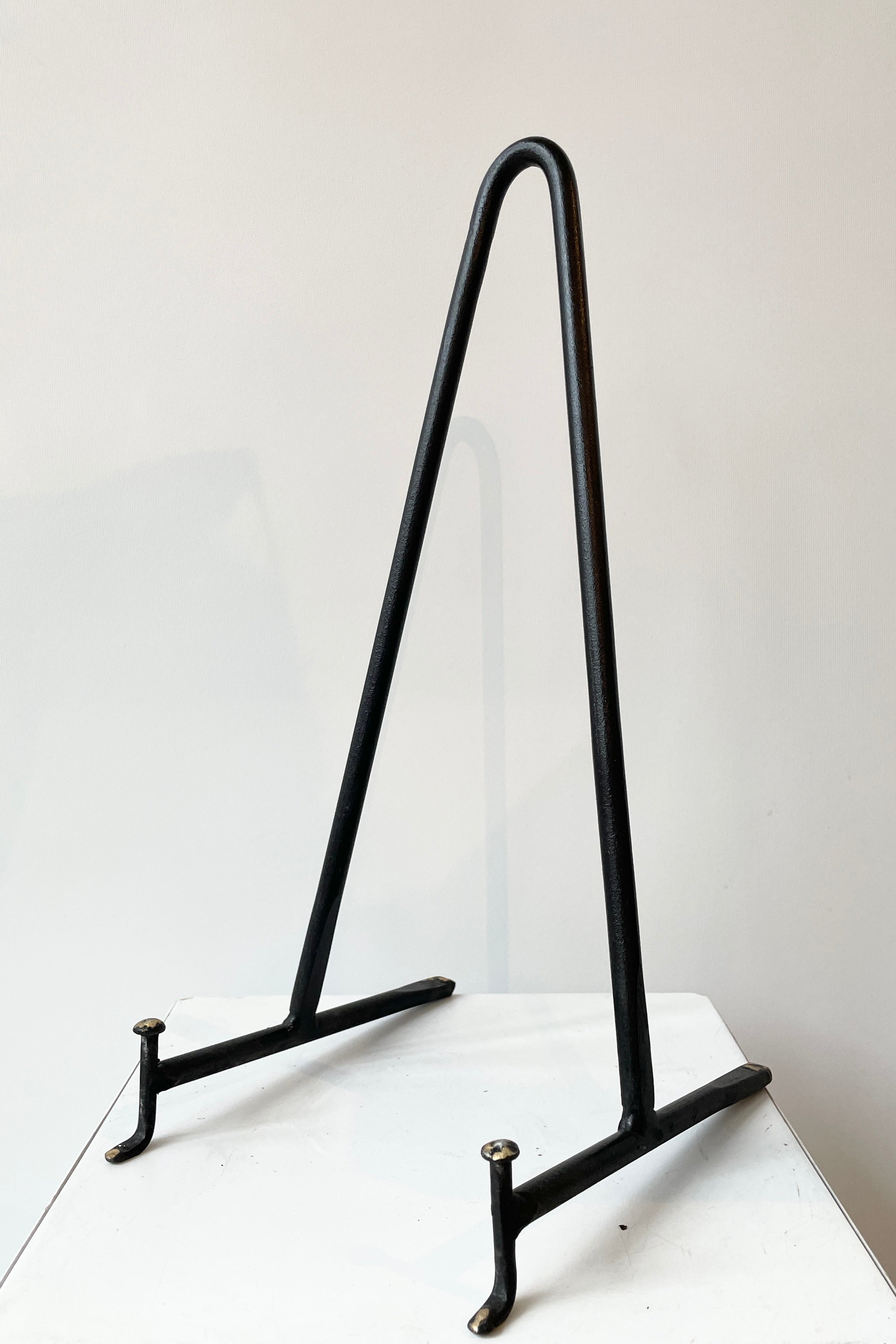 The large cast iron display stand sitting against a white wall.
