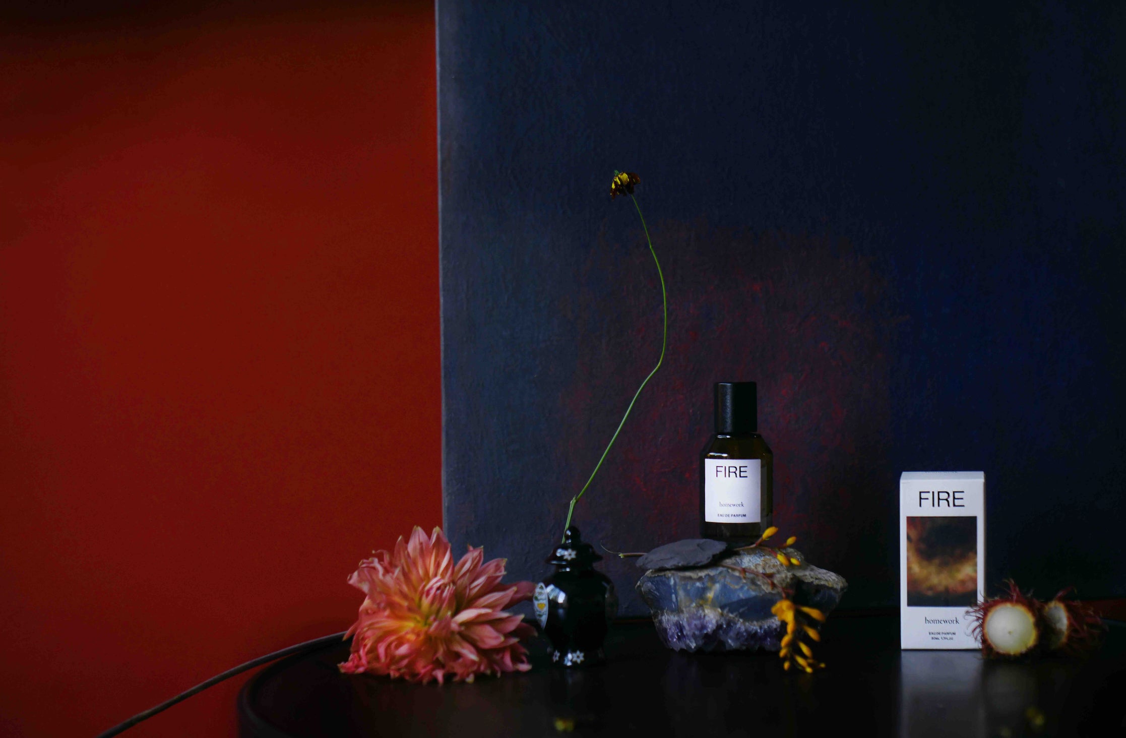 Bottle and box labeled 'FIRE' on a dark surface with a red and blue background ©Homework