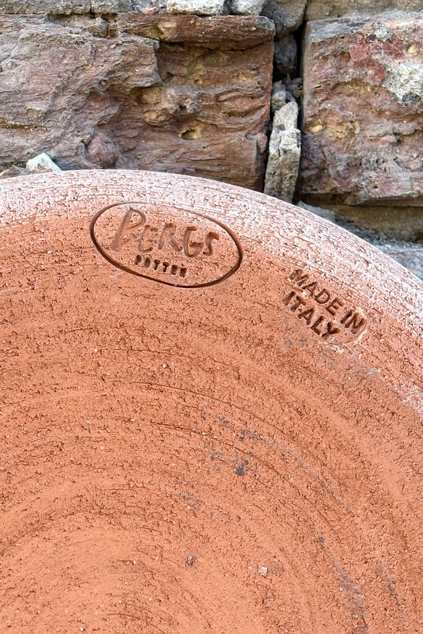 Detail on bottom of saucer stamped with Bergs potter logo and made in Italy against an exposed brick wall ©Sprout Home