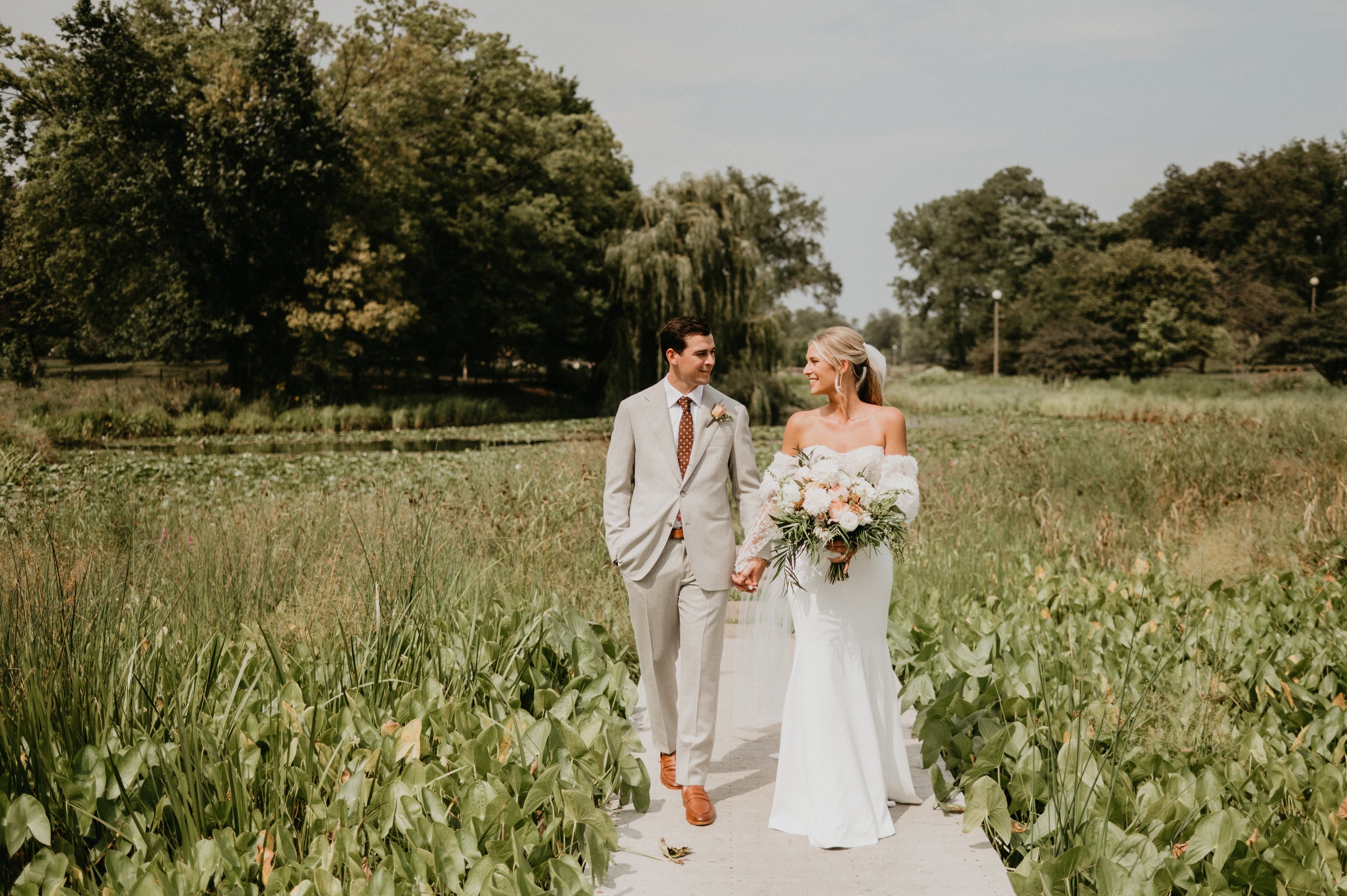Kathryn Conner wedding with the couple on a walkway in the middle of a marshy forest preserve. floral by Sprout Home. Photograph by Lauren Dixon Photo