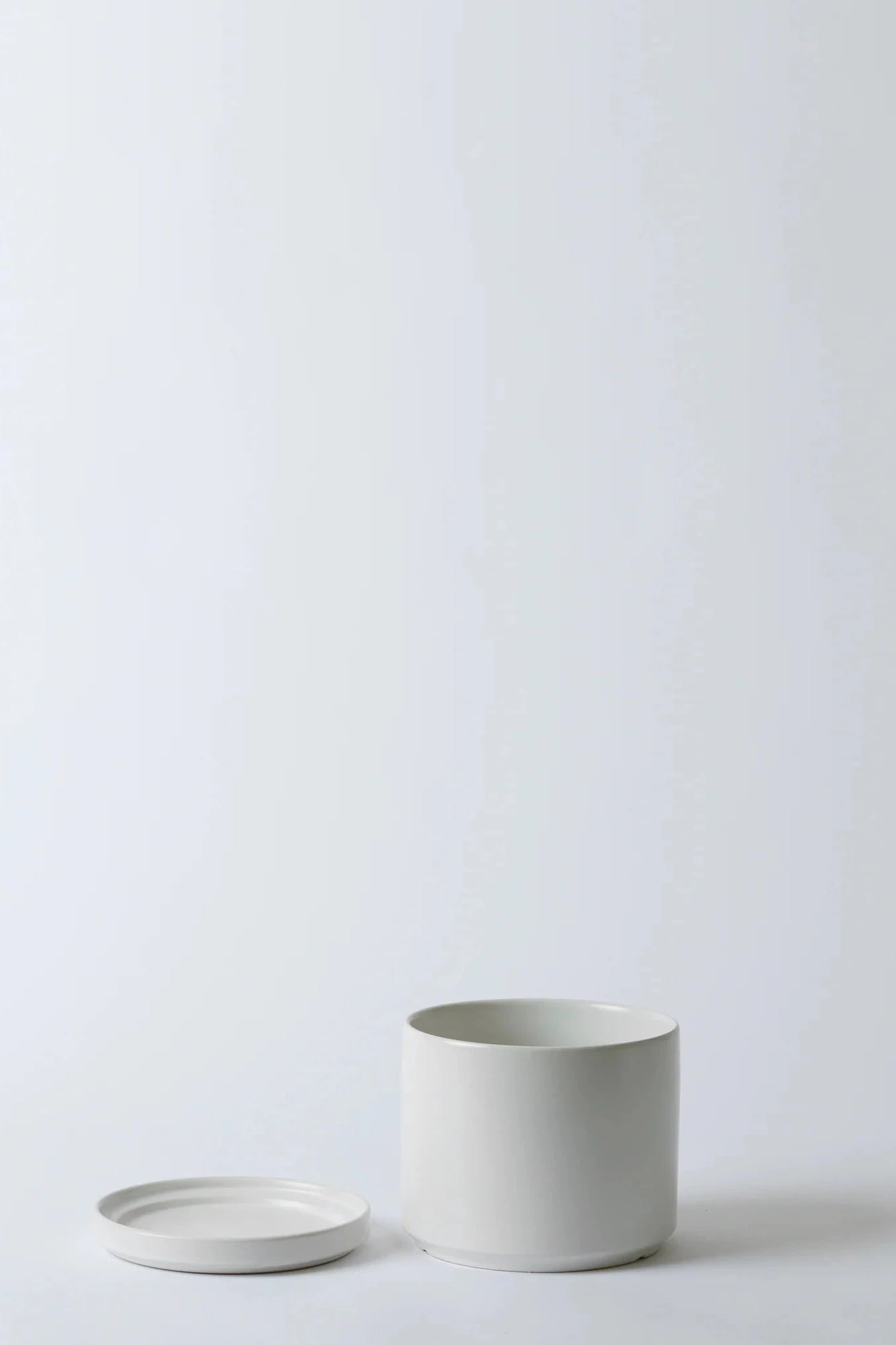 LBE Design Solid Goods planter and saucer in white with the pot and saucer laying next to each other.