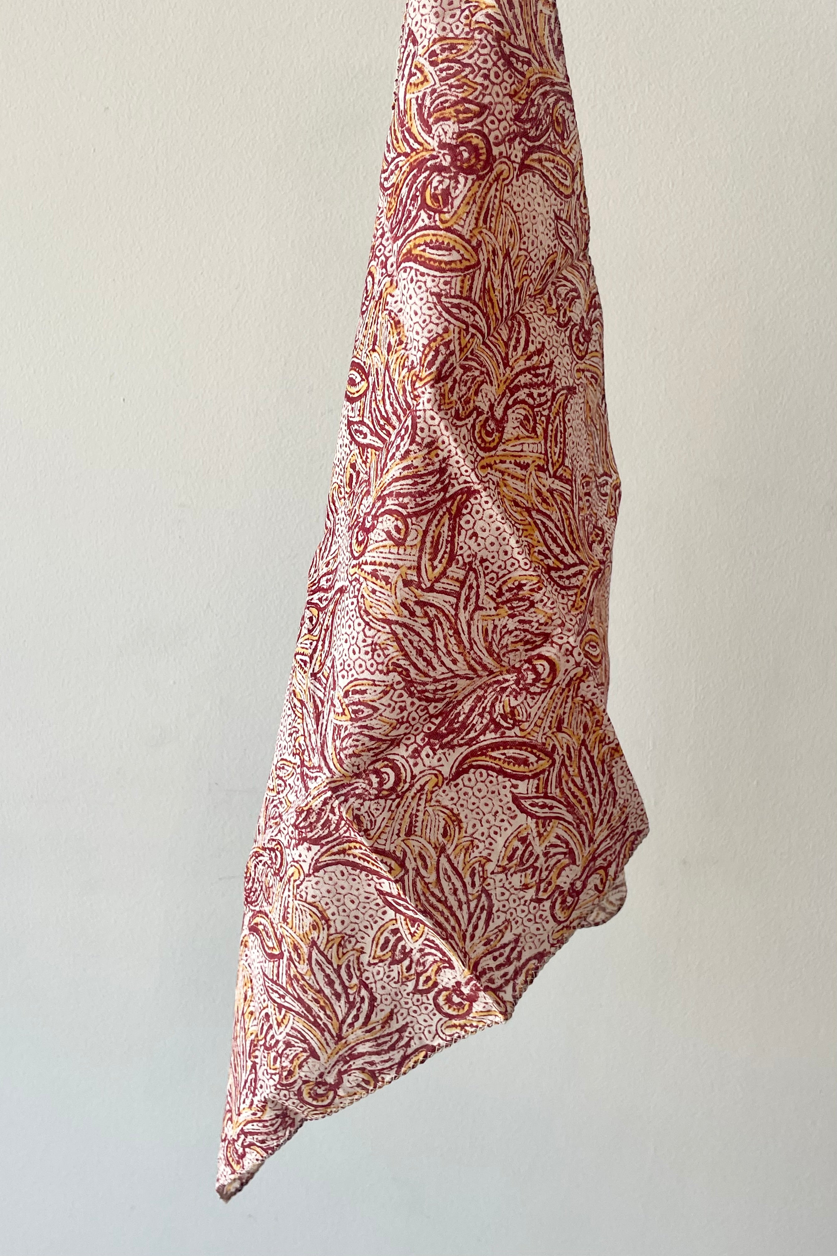 Holding an Acacia pattern napkin against a white wall.
