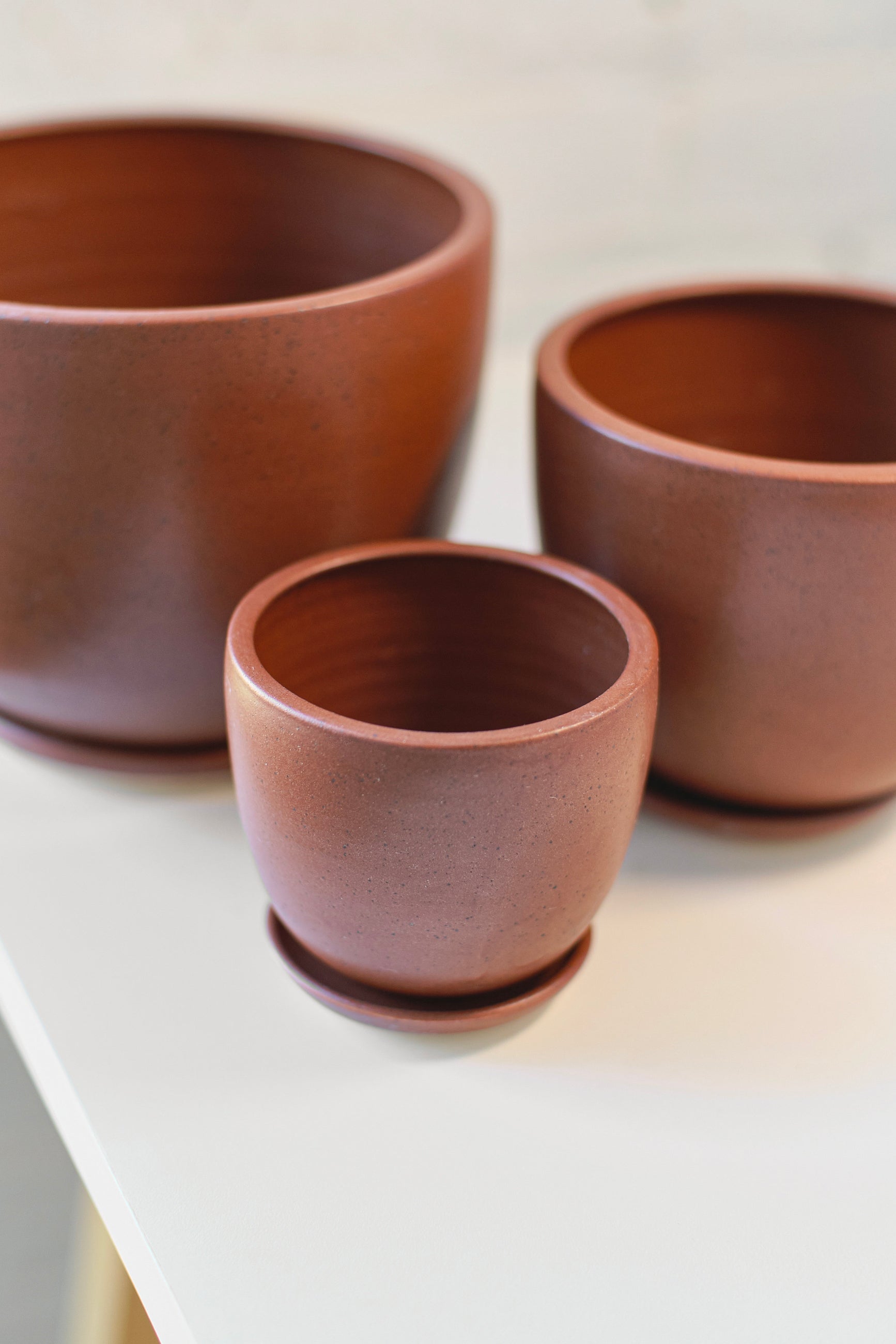 Three brown speckle tabletop pots of different sizes on a light surface. ©Little Fire Ceramics