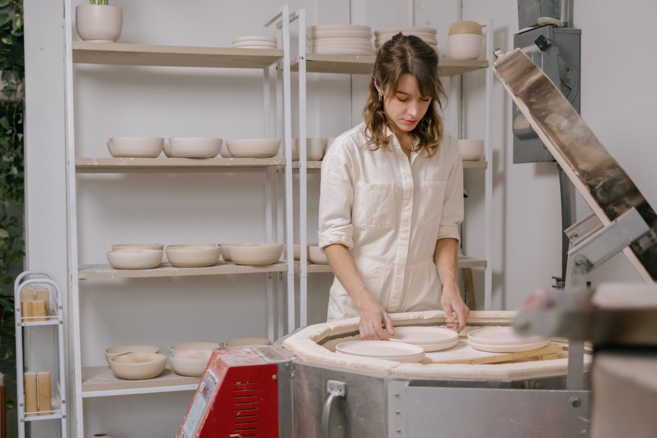 The artist of Little Fire Ceramics, Jessica, at her kiln and dressed in white ©Little Fire Ceramics