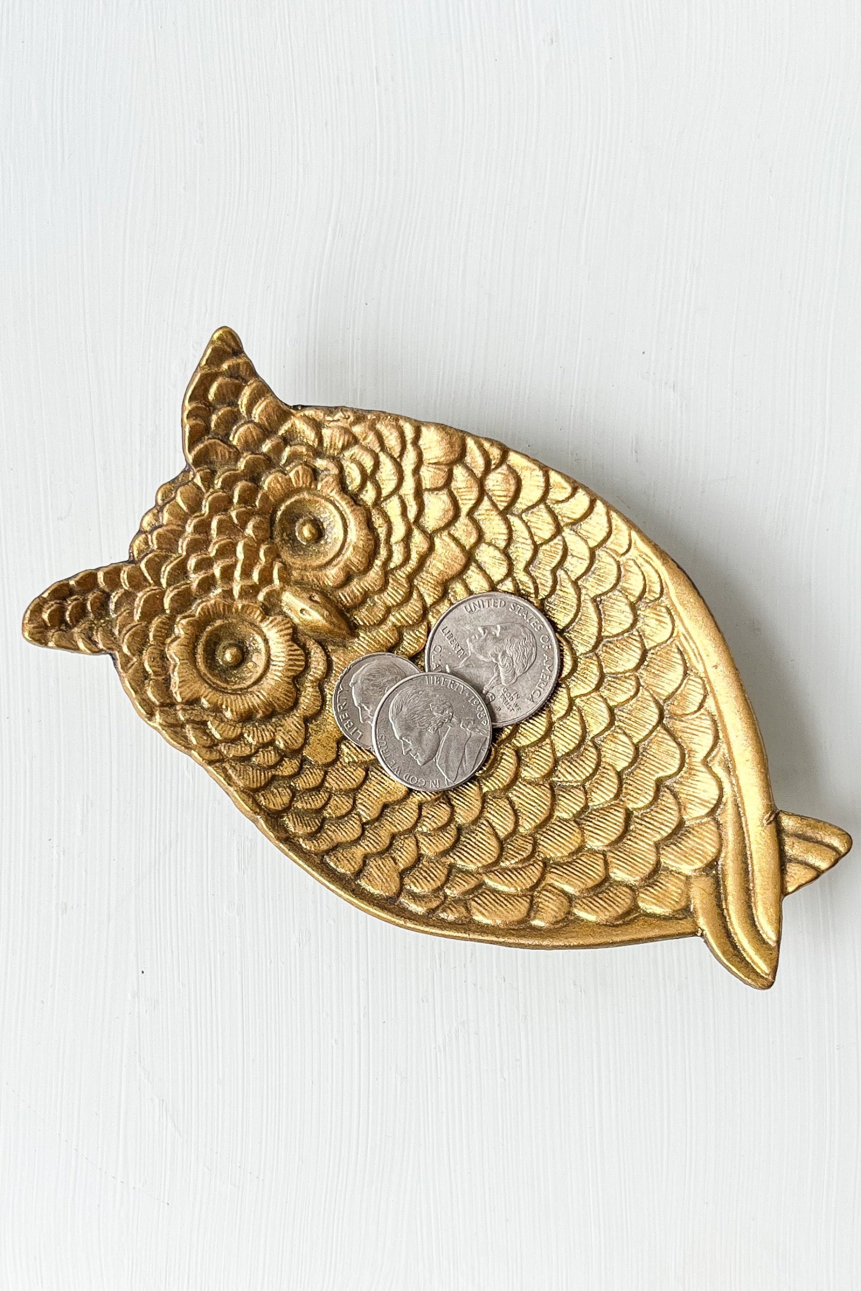 Gold owl-shaped trinket dish with coins on a white background ©Sprout Home