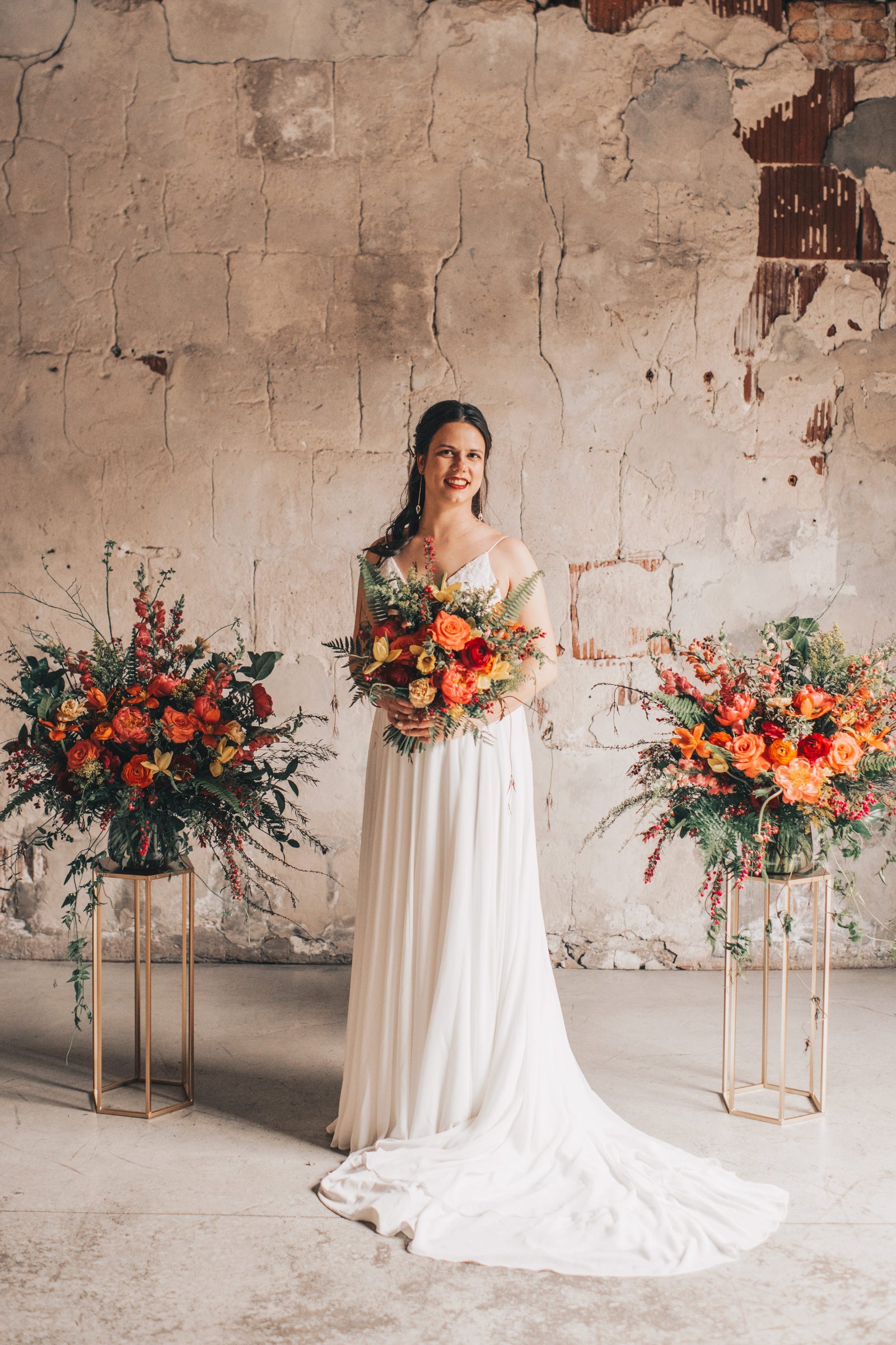 Wedding floral of warm reds and oranges with two larger alter arrangements and the bride with a bridal bouquet a the Charcoal Loft in Chicago. floral designed by Sprout Home. Photography by Julia Marumaya Photography.
