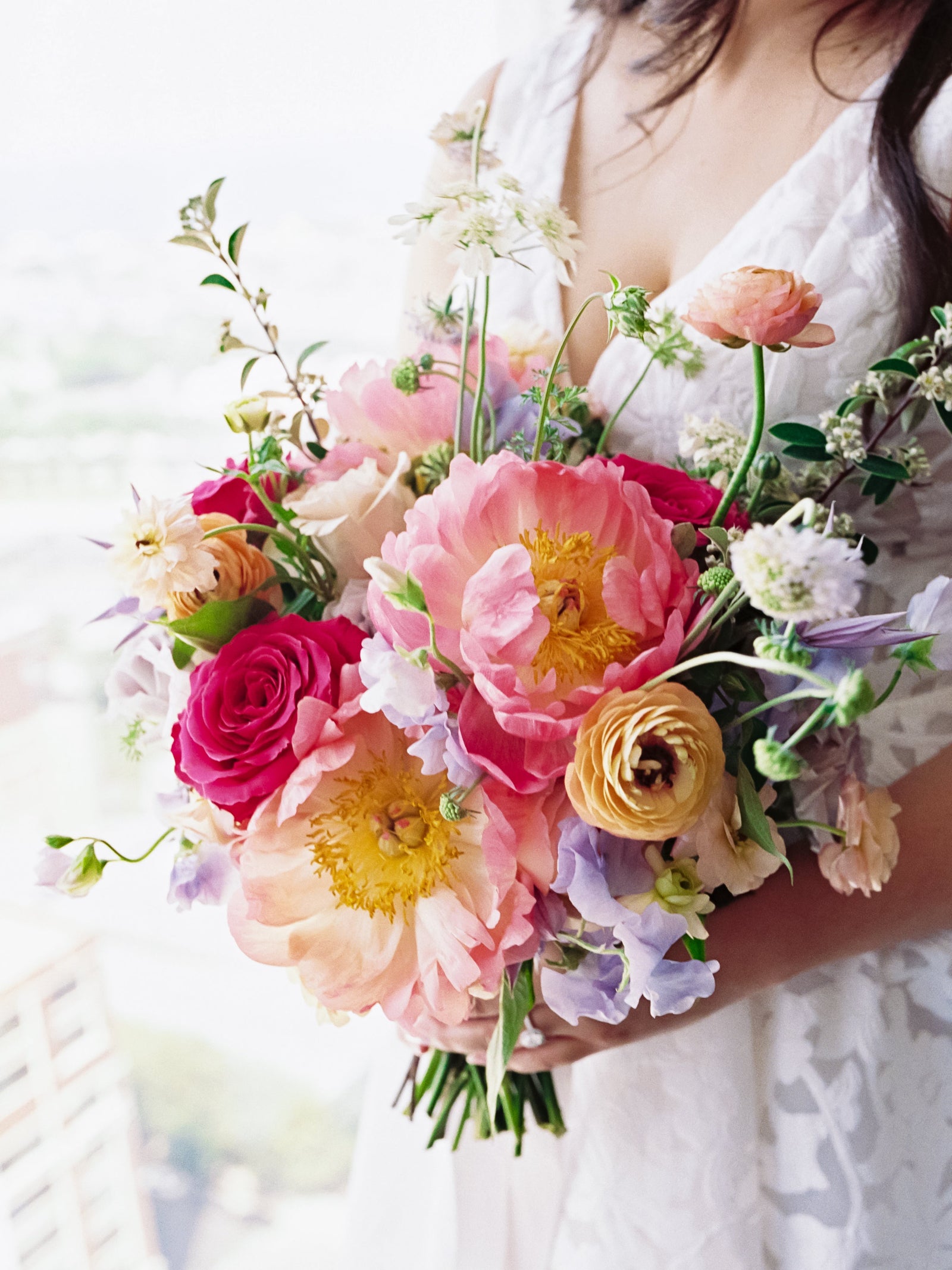 Dominick wedding with the bride holding a bright colorful bridal bouquet featuring peony and ranunculus. Playful and fun bouquet. Floral by Sprout Home. Photograph by Armenteros Weddings