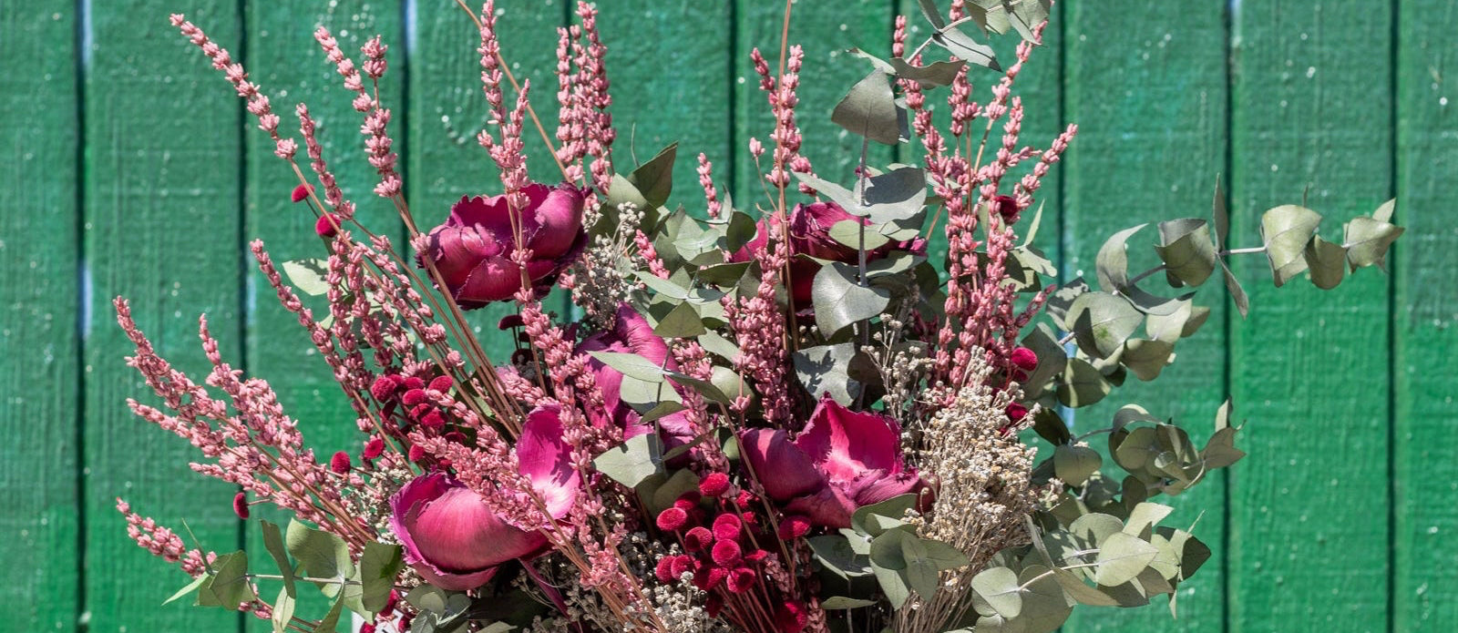 Bouquet of flowers held against a green wooden background ©Sprout Home