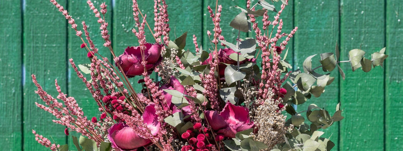 Bouquet of flowers held against a green wooden background ©Sprout Home