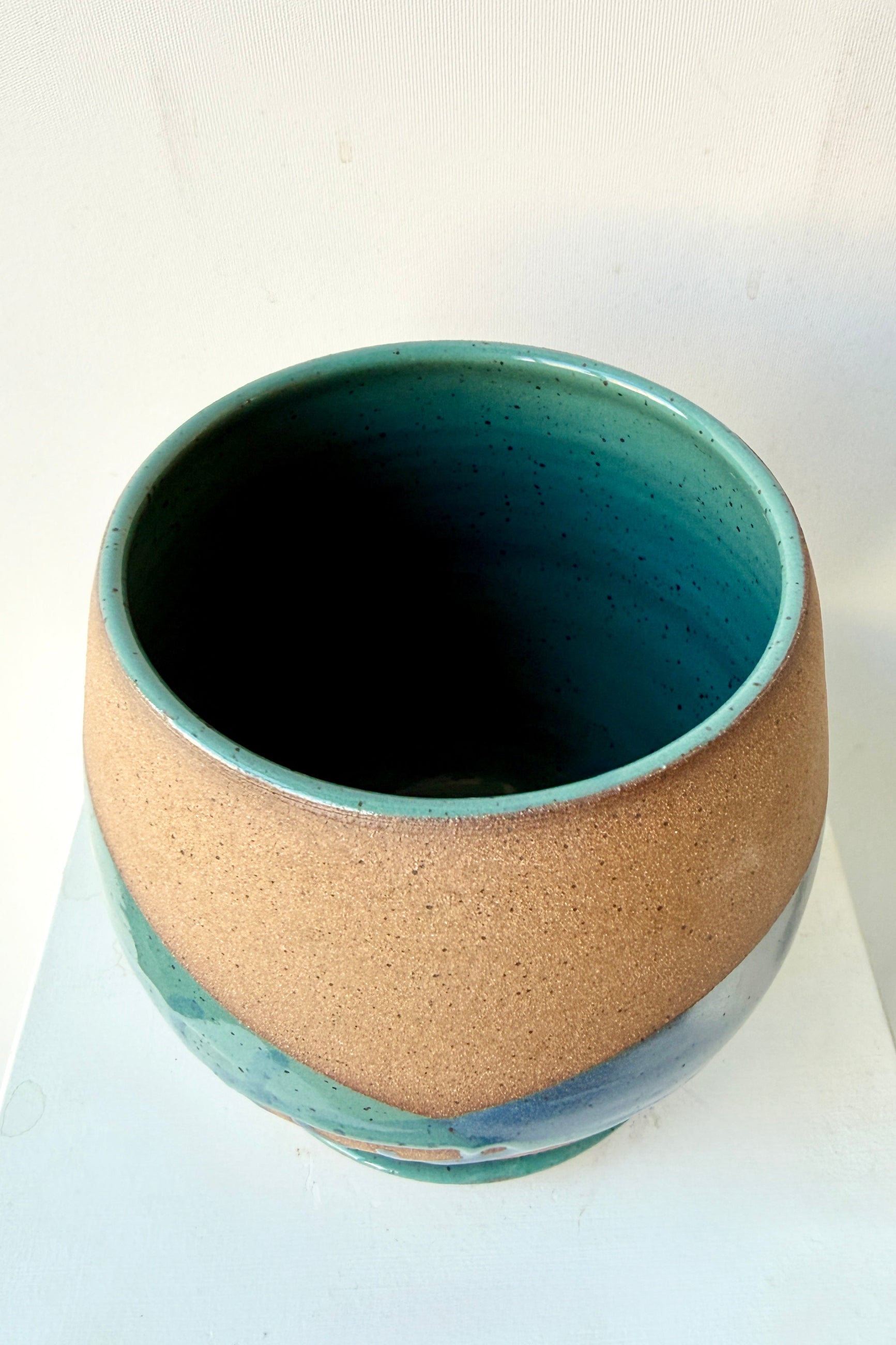 Ceramic planter with two-tone design by Christina Kosinski on a white background looking inside from above at the teal interior glaze ©Sprout Home