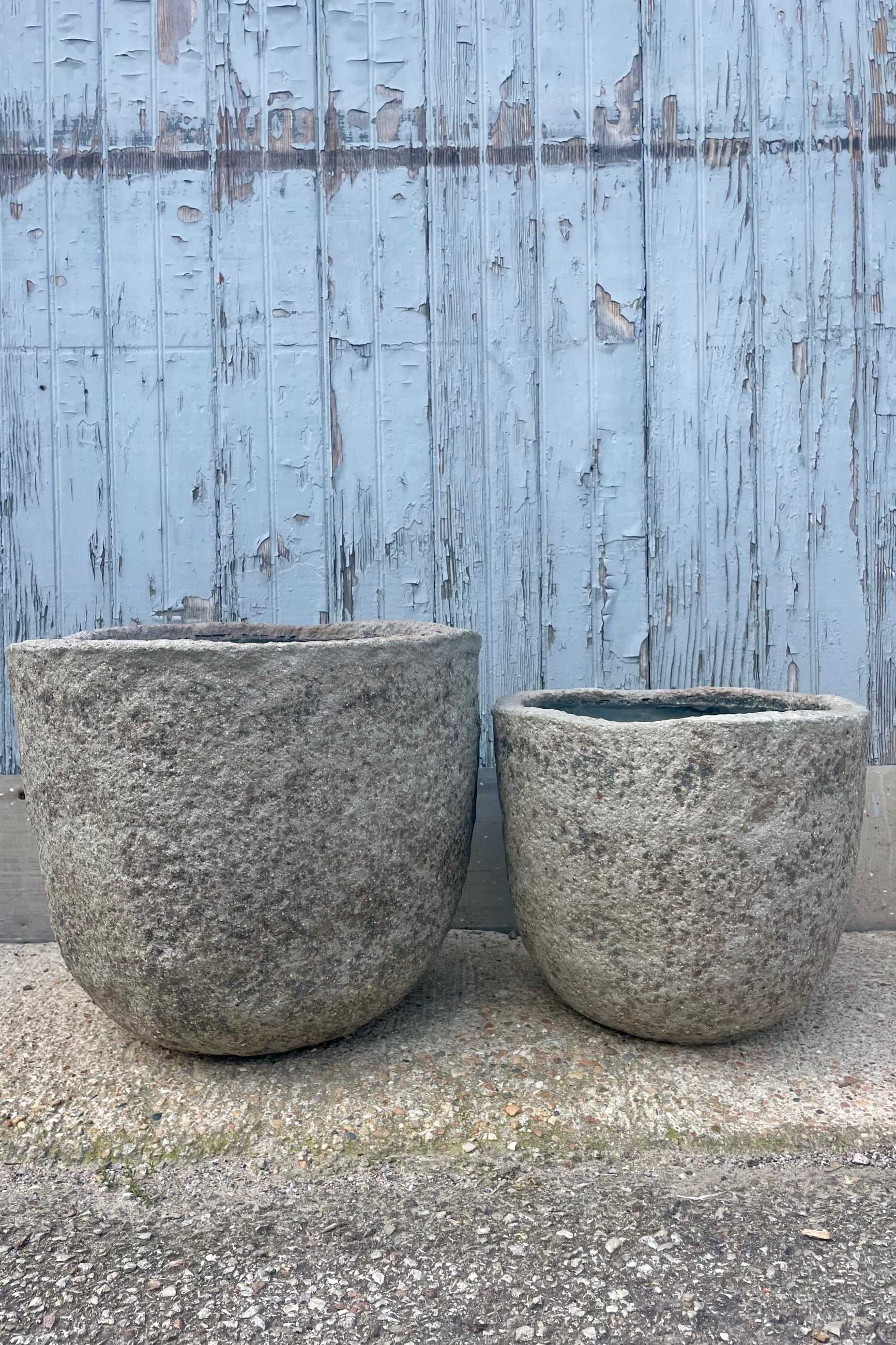 A pair of gray textured planters in front of a wooden wall. ©Sprout Home