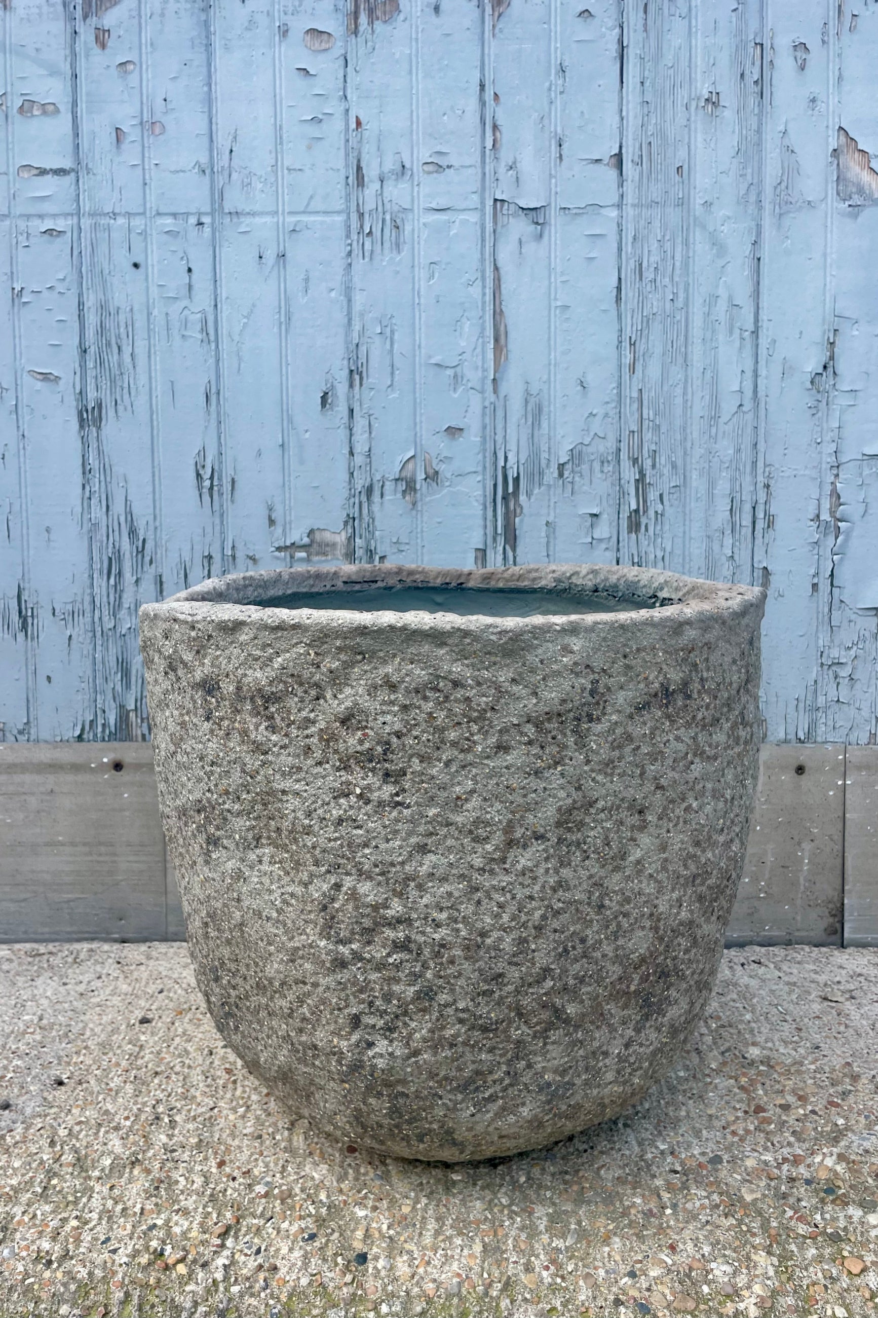 A textured gray pot in front of a wooden wall ©Sprout Home
