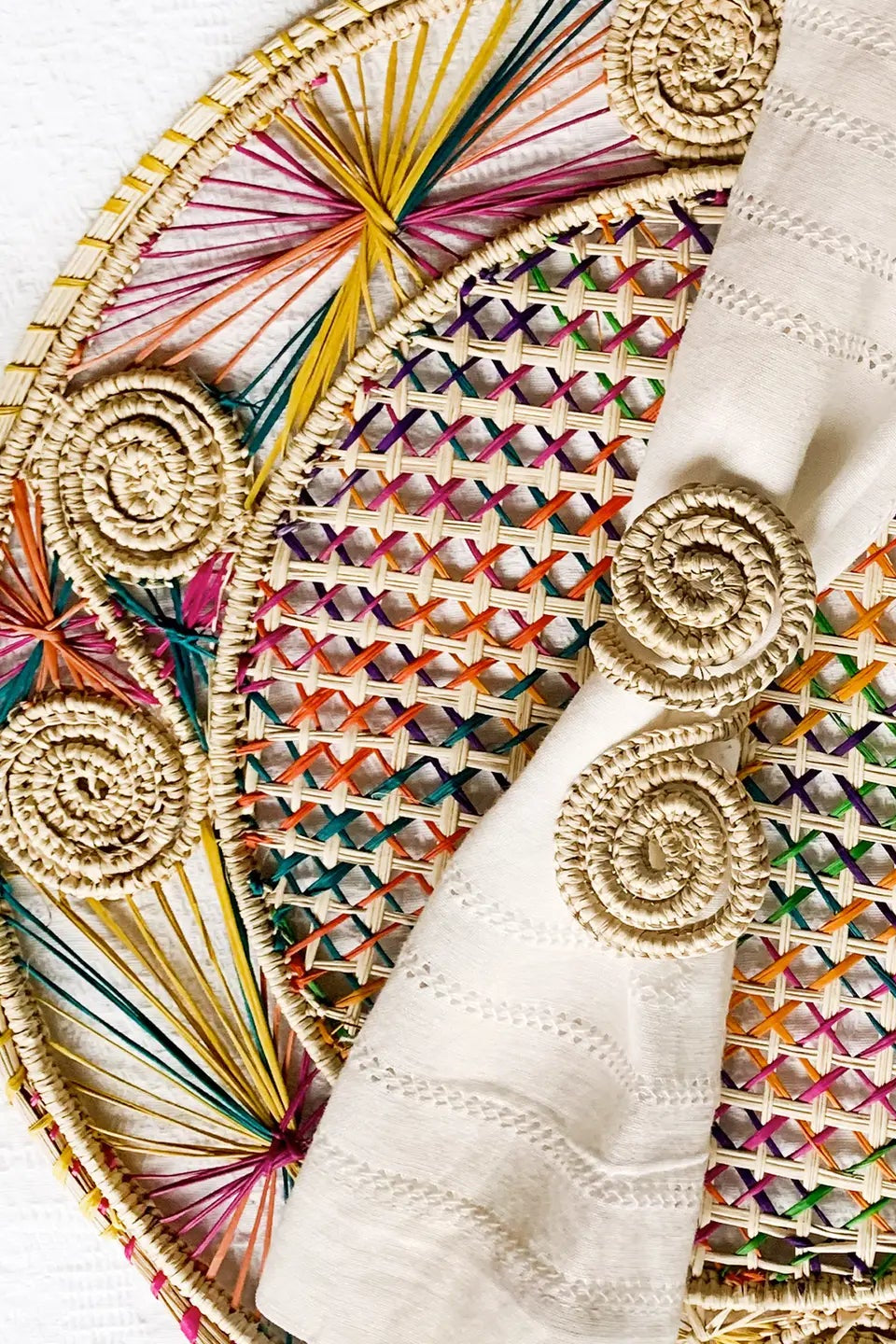Photo of a natural fiber placement in front of a white background. The placemat is made by Coro Cora and is natural white with bright multicolor accents.