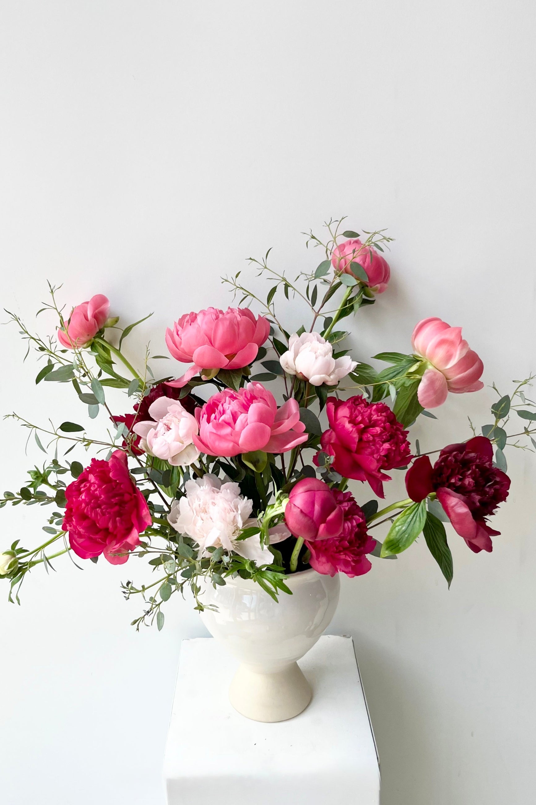 Bouquet of pink, red, and white Peony flowers in a white vase on a white background ©Sprout Home #size_$200