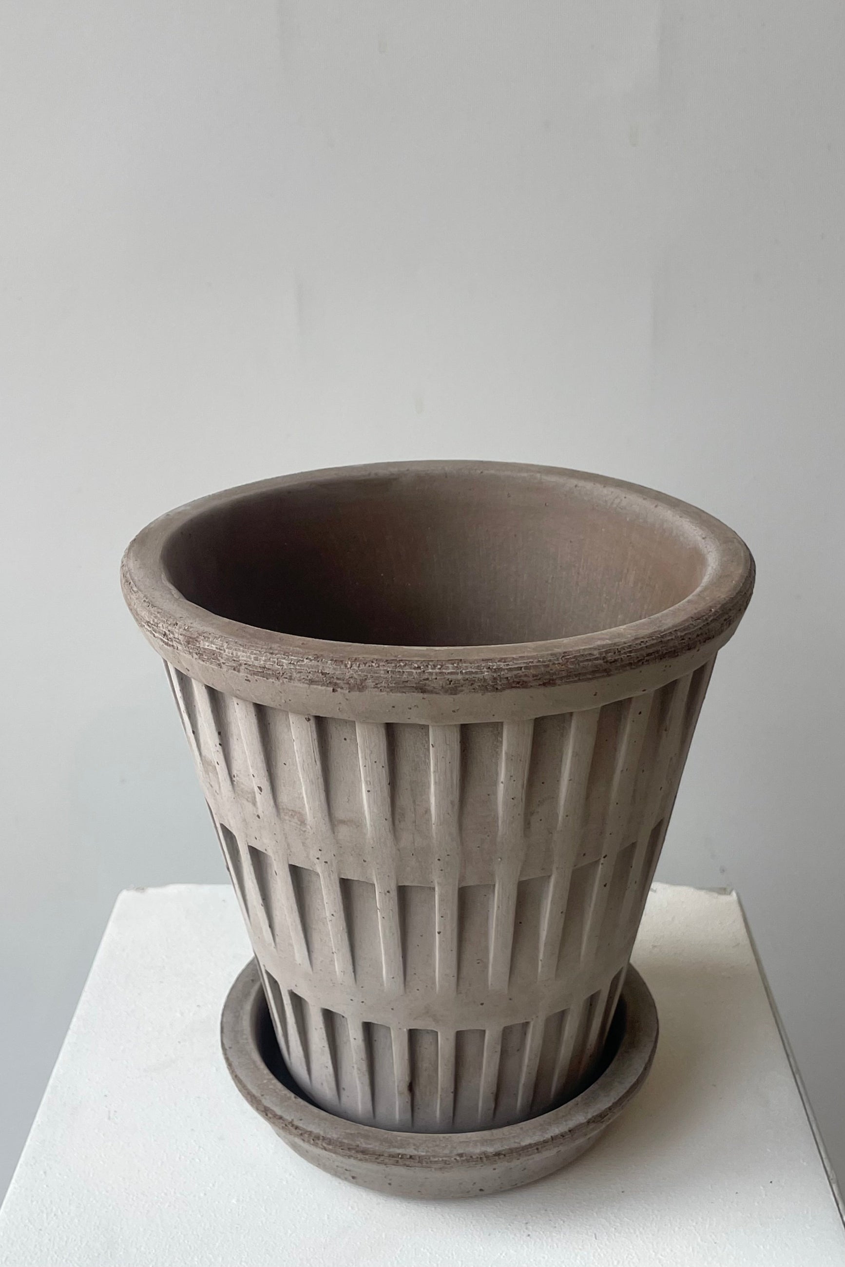 A gray clay pot and saucer shown from above in a white room ©Sprout Home