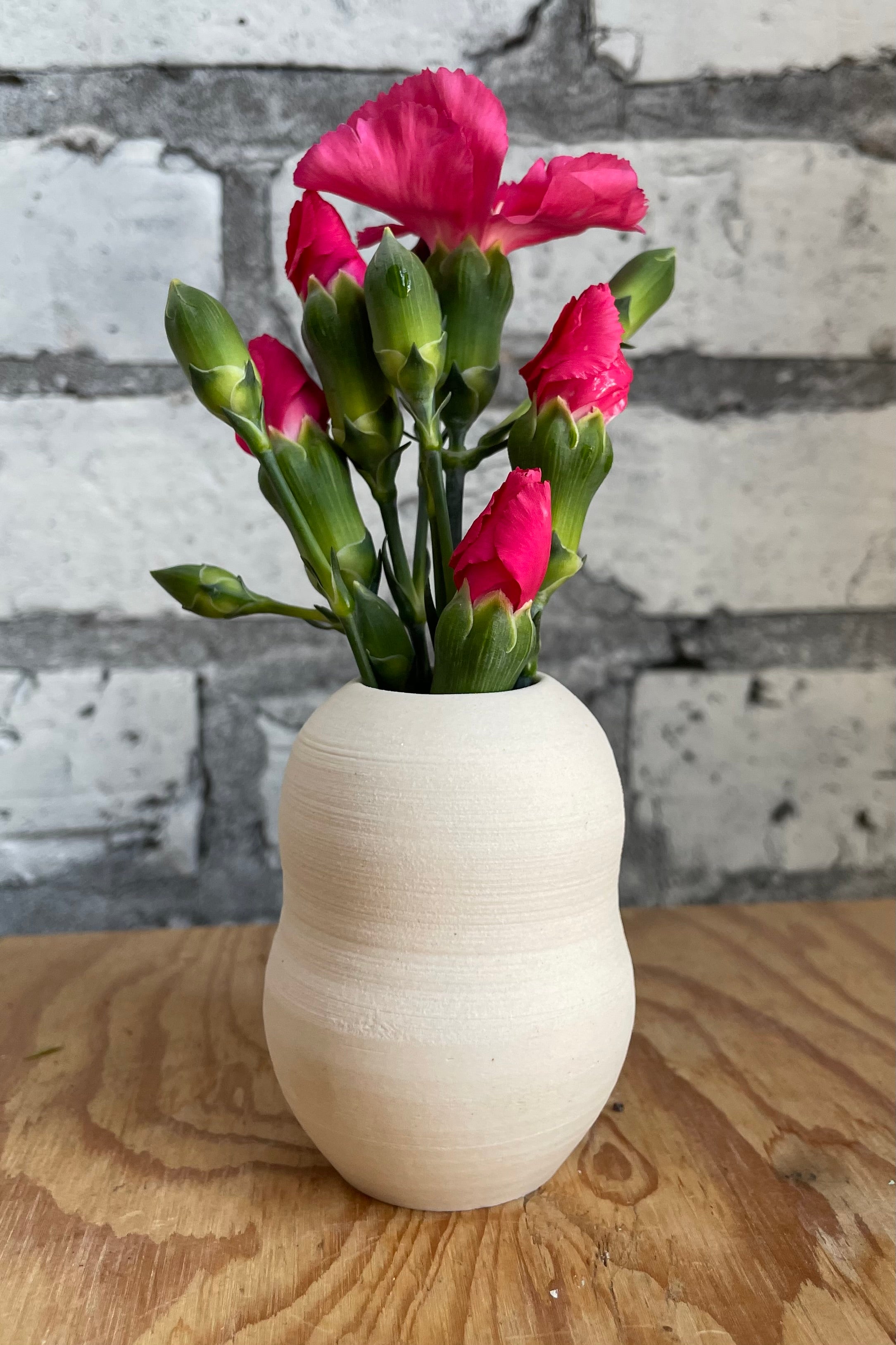 Petite pastel bubble vase in eggshell on a wood surface and pink flowers.