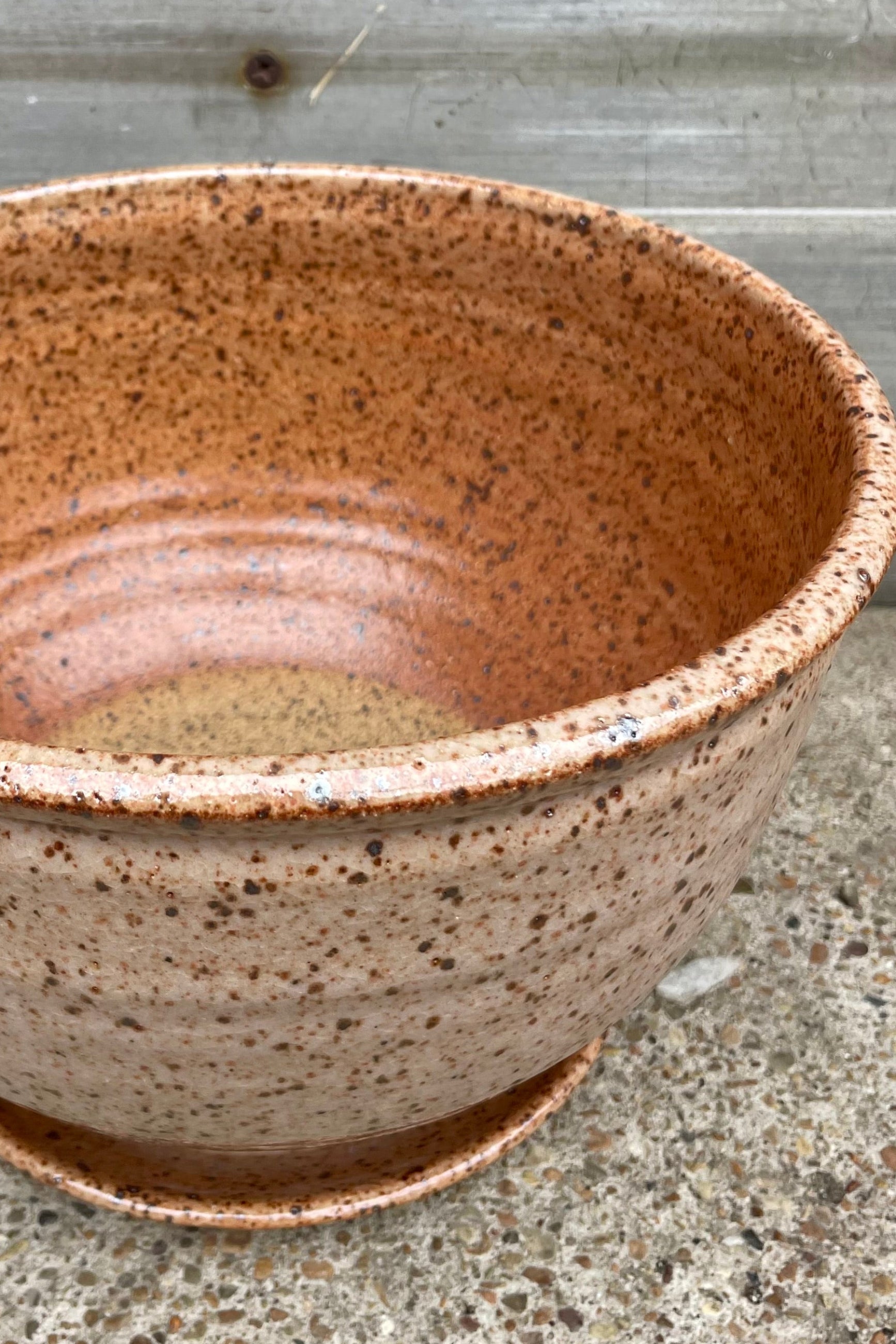 View looking down. A tan speckled planter in front of a wooden wall ©Sprout Home