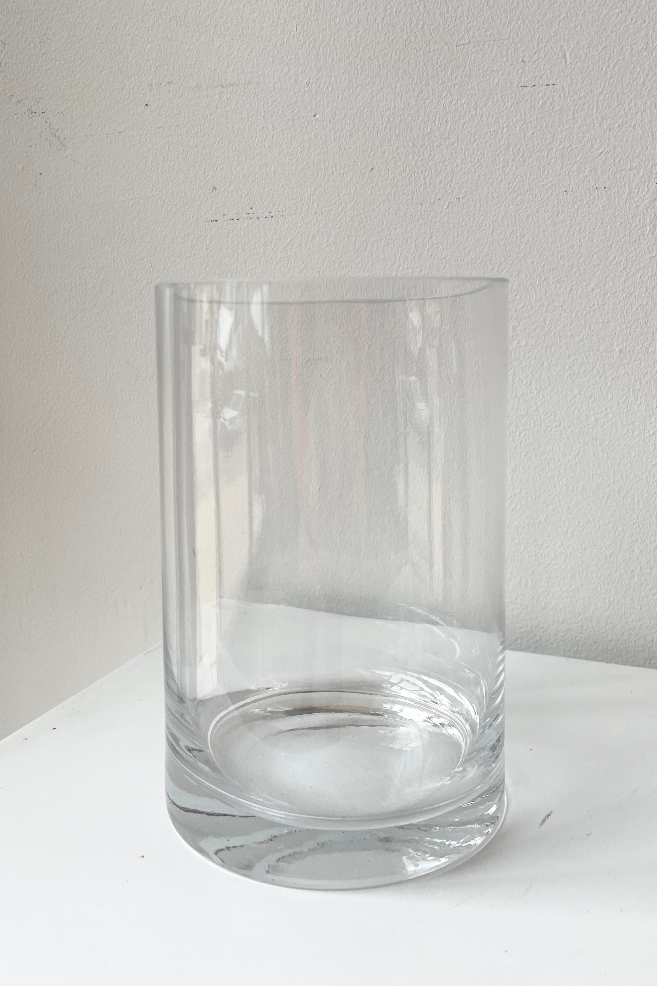 A clear vase 6x4 sitting on a white pedestal looking from the side.
