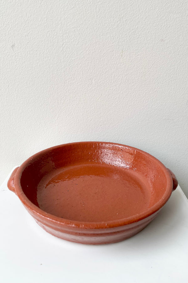 Small terra cotta roasting dish sitting on a white surface looking from the side and above.