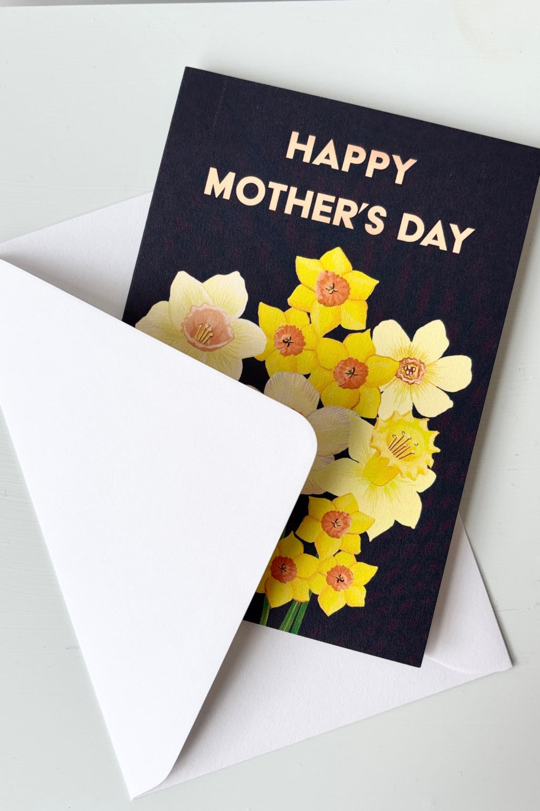 Greeting card with yellow daffodils on a black background with the words Happy Mother's Day on the front. Shown with envelope ©Sprout Home