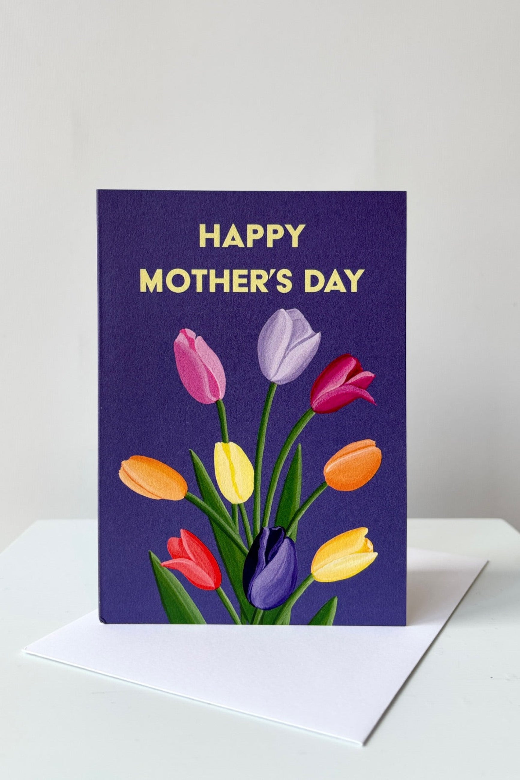 Greeting card with multicolored tulips on a purple background with the text Happy Mother's Day shown with envelope ©Sprout Home