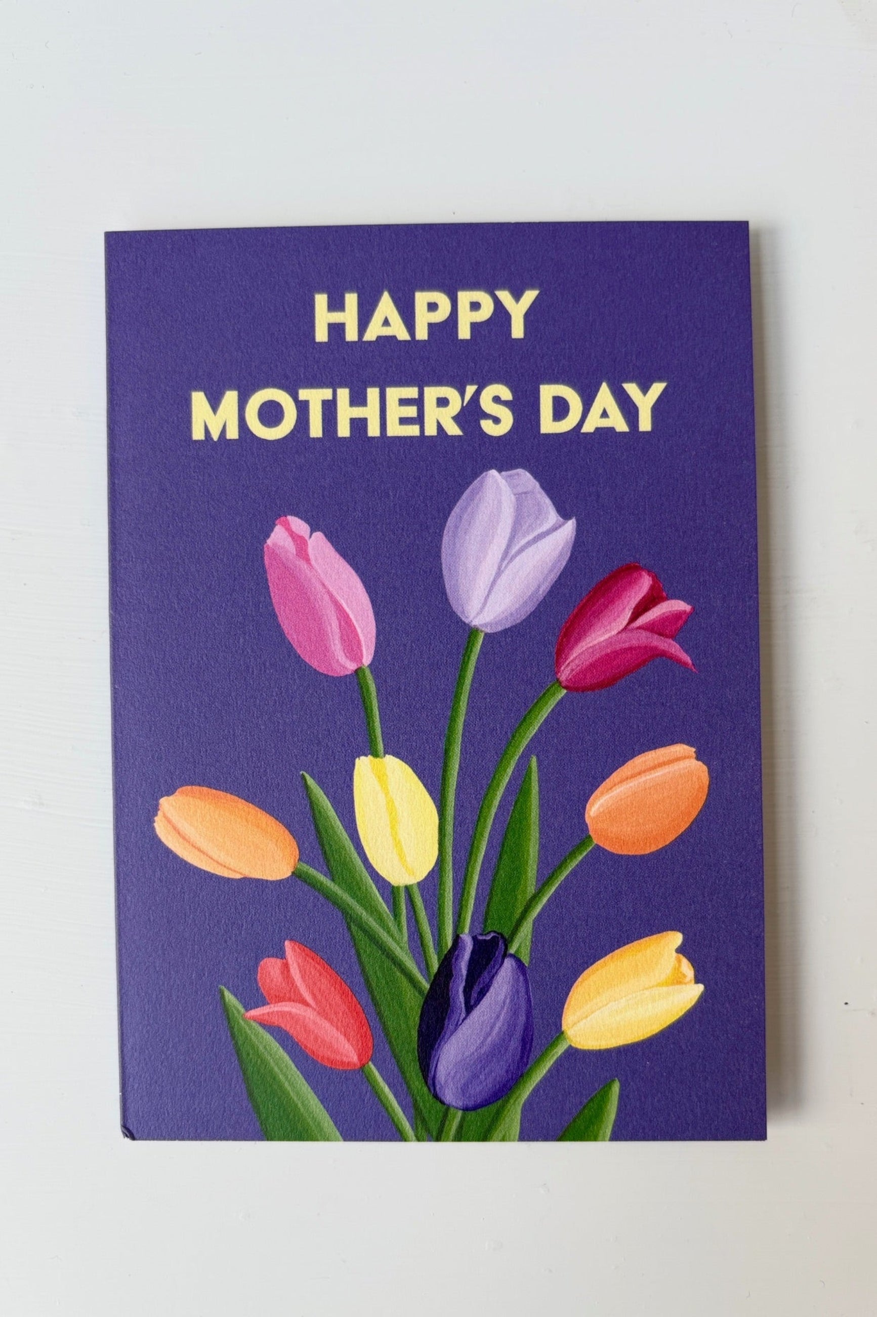 Greeting card with multicolored tulips on a purple background with the text Happy Mother's Day shown with envelope ©Sprout Home