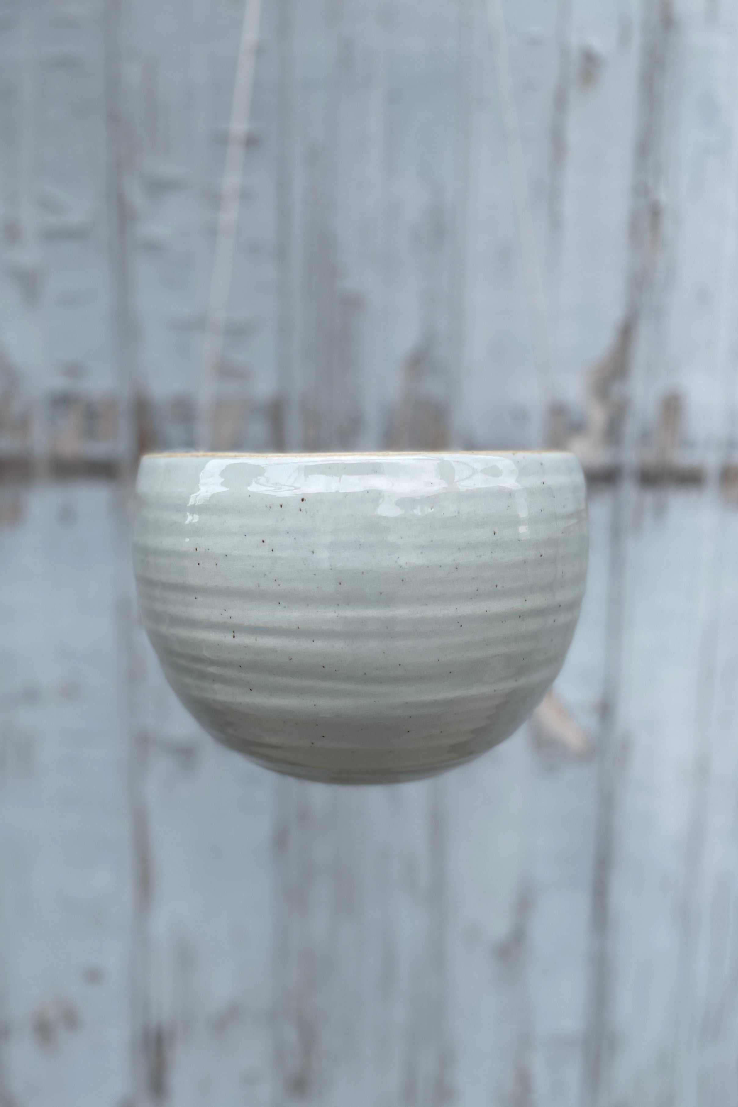 The Spherical hanging planter in grey crackle, hanging empty and viewed from the side.