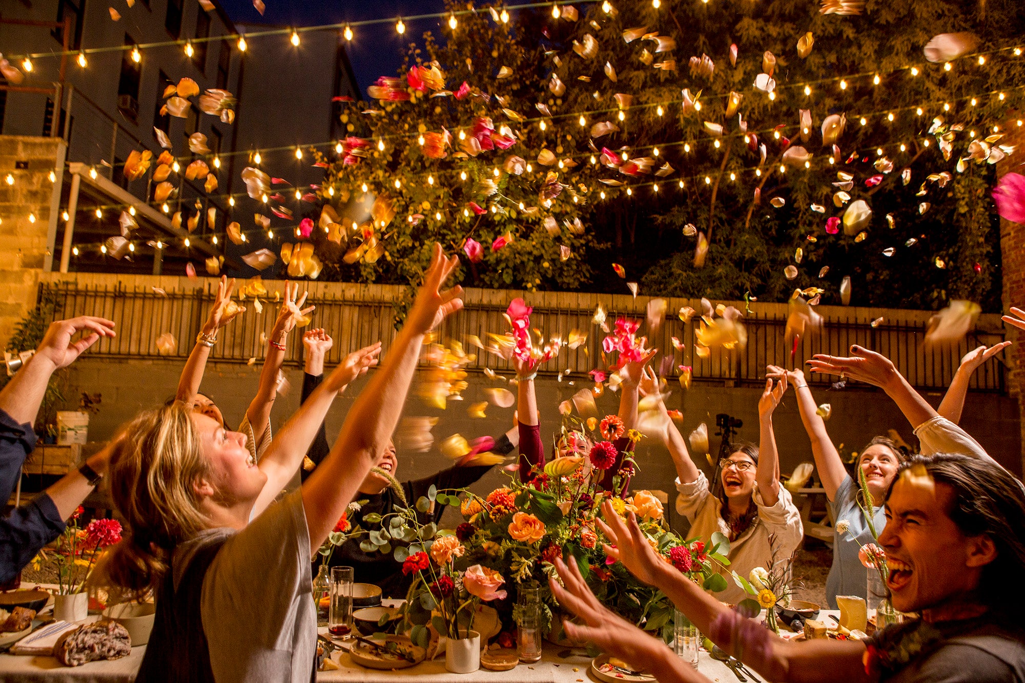 Garden party with floral on the table and in the air amongst garden lights. Floral by SPROUT HOME. Photo by Noah Kalina