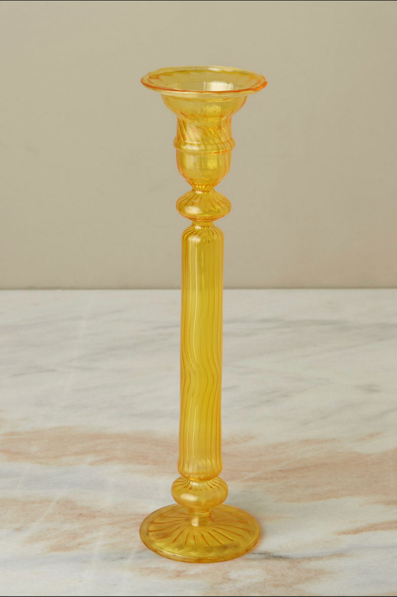 A daffodil Nahlia glass candlestick holder on a gray peach marble counter.