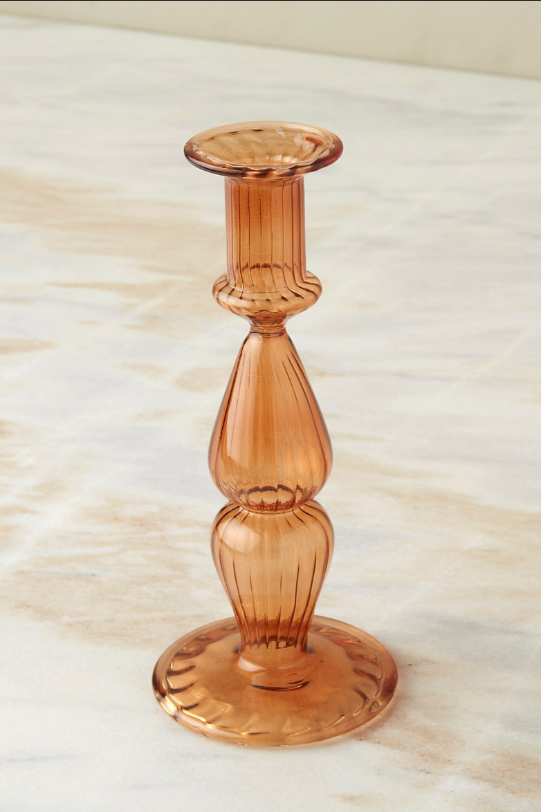 Nahlia Marmalade glass candlestick holder on a white and peach marble counter.