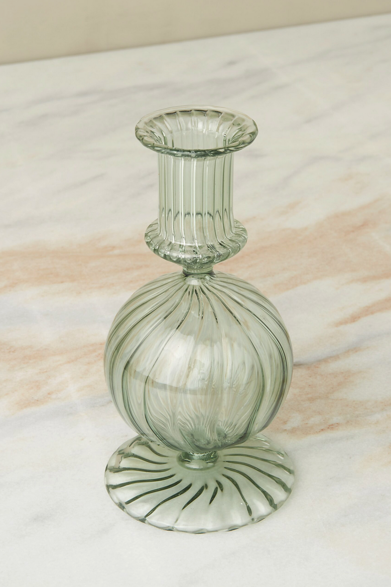 Parakeet Nahlia glass taper candlestick holder, empty and sitting on a marble counter.