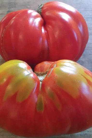 Two large red Stone Ridge tomatoes on a wooden surface ©Hudson Valley Seed Co.