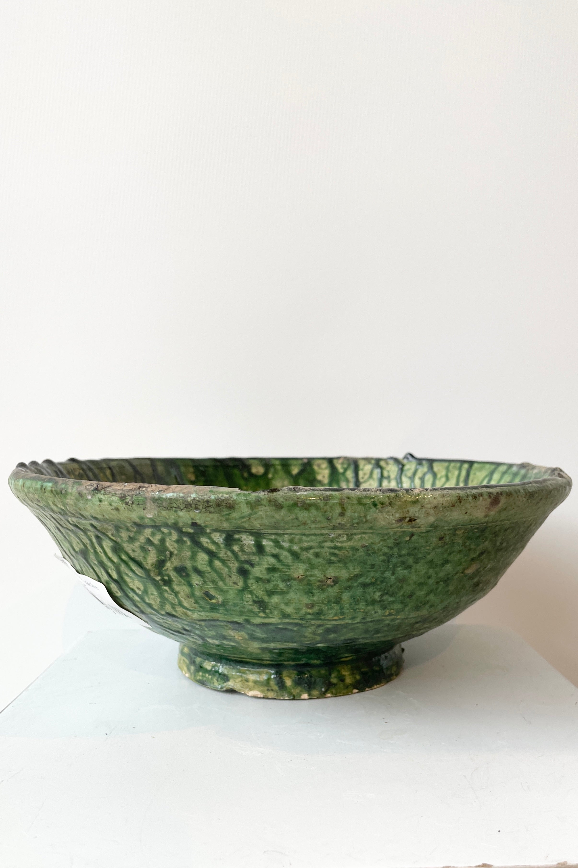 The Green medium Tamegroute bowl shown from the side against a white wall at Sprout Home.