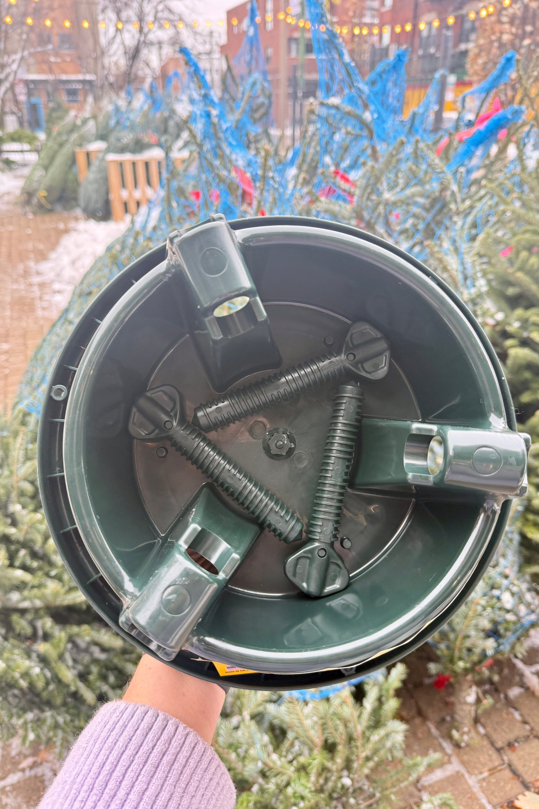 Metal bracket or component held by a person with a colorful outdoor background ©Sprout Home