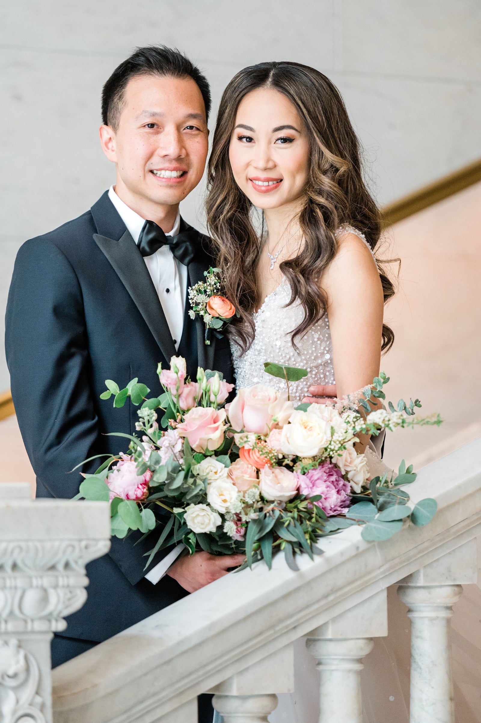 Yan and Andrew wedding at the Ivy Room in Chicago. Portrait of the bride and groom on a staircase holding a bridal bouquet featuring eucalyptus, cream and pink roses and peony amongst other floral by SPROUT HOME. Photograph by Ana Maria Vieriu Photography