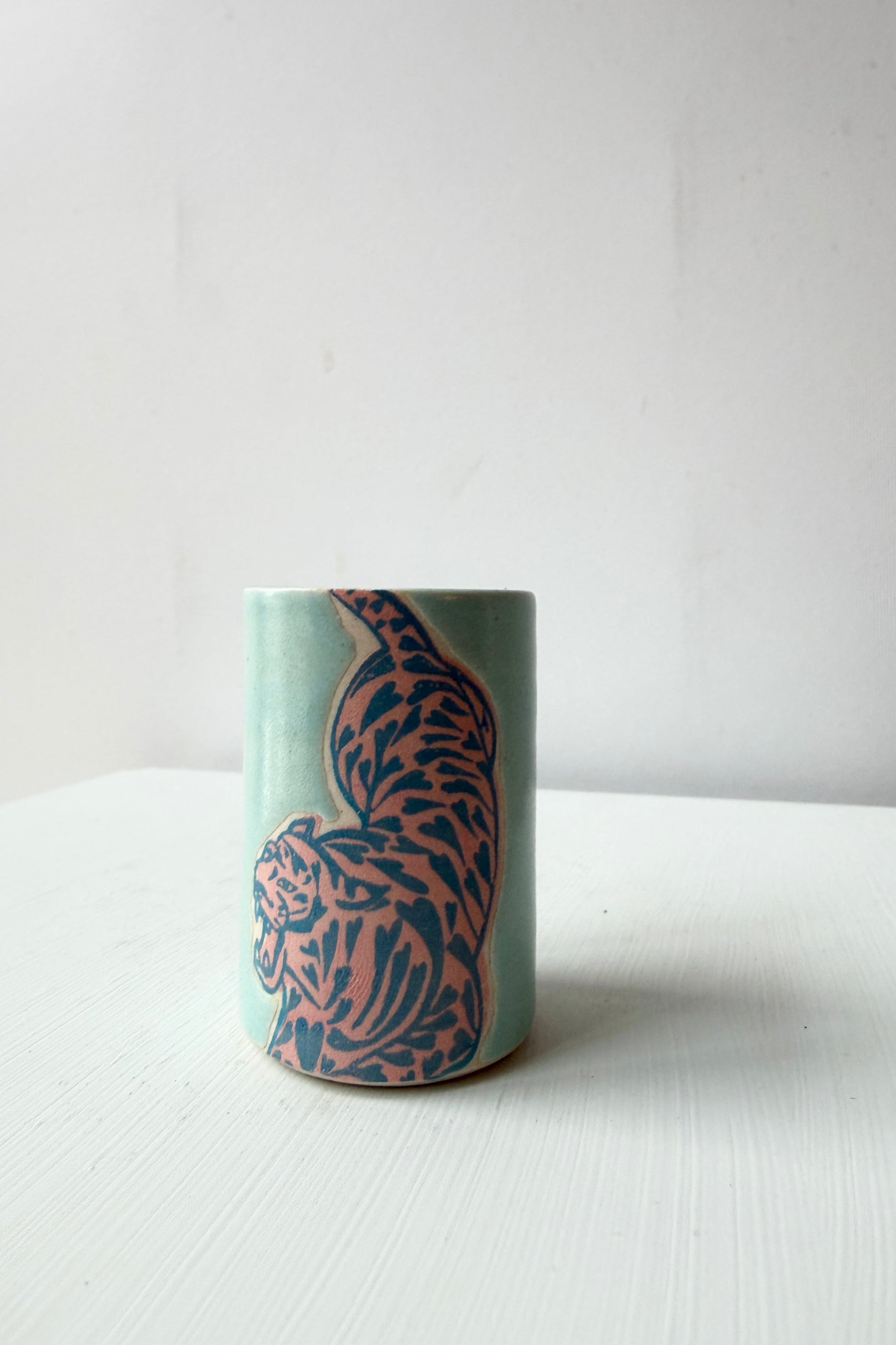 Cylindrical ceramic tiger cup by City in Bloom Ceramics with a blue and pink tiger pattern on a white background ©Sprout Home