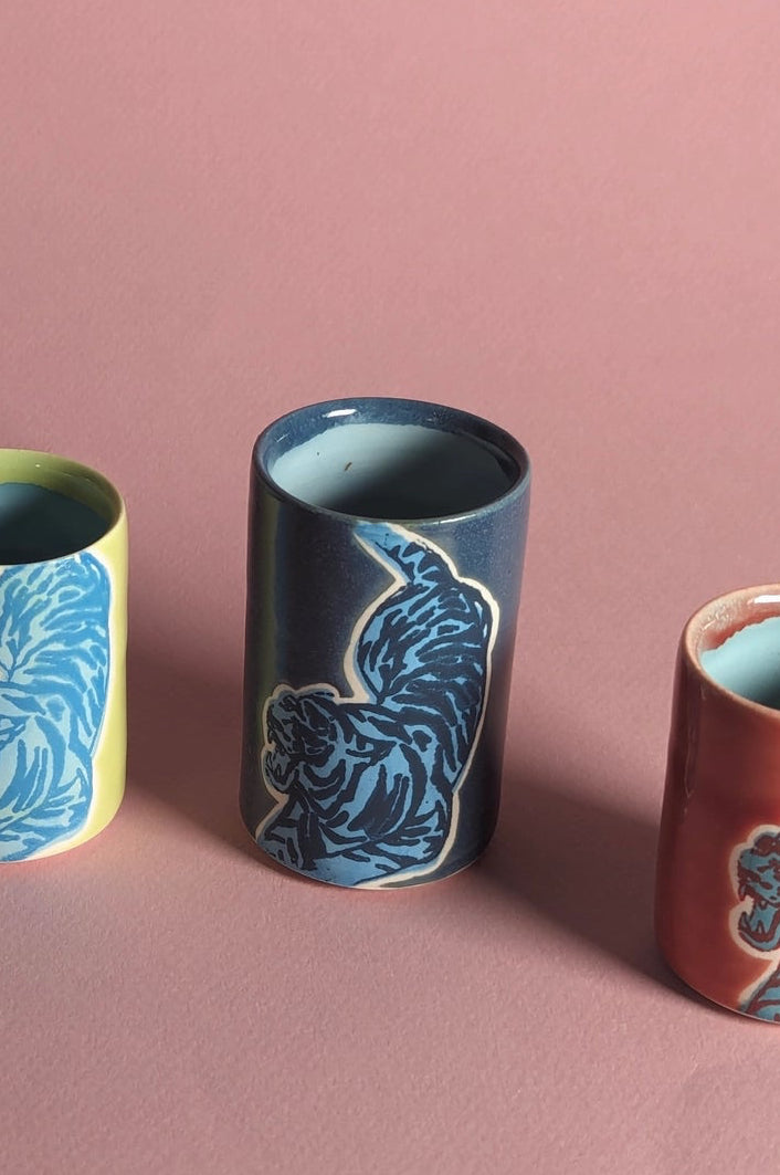 ceramic cups with animal patterns on a pink background featuring a dark blue on blue one in the center ©City In Bloom Ceramics