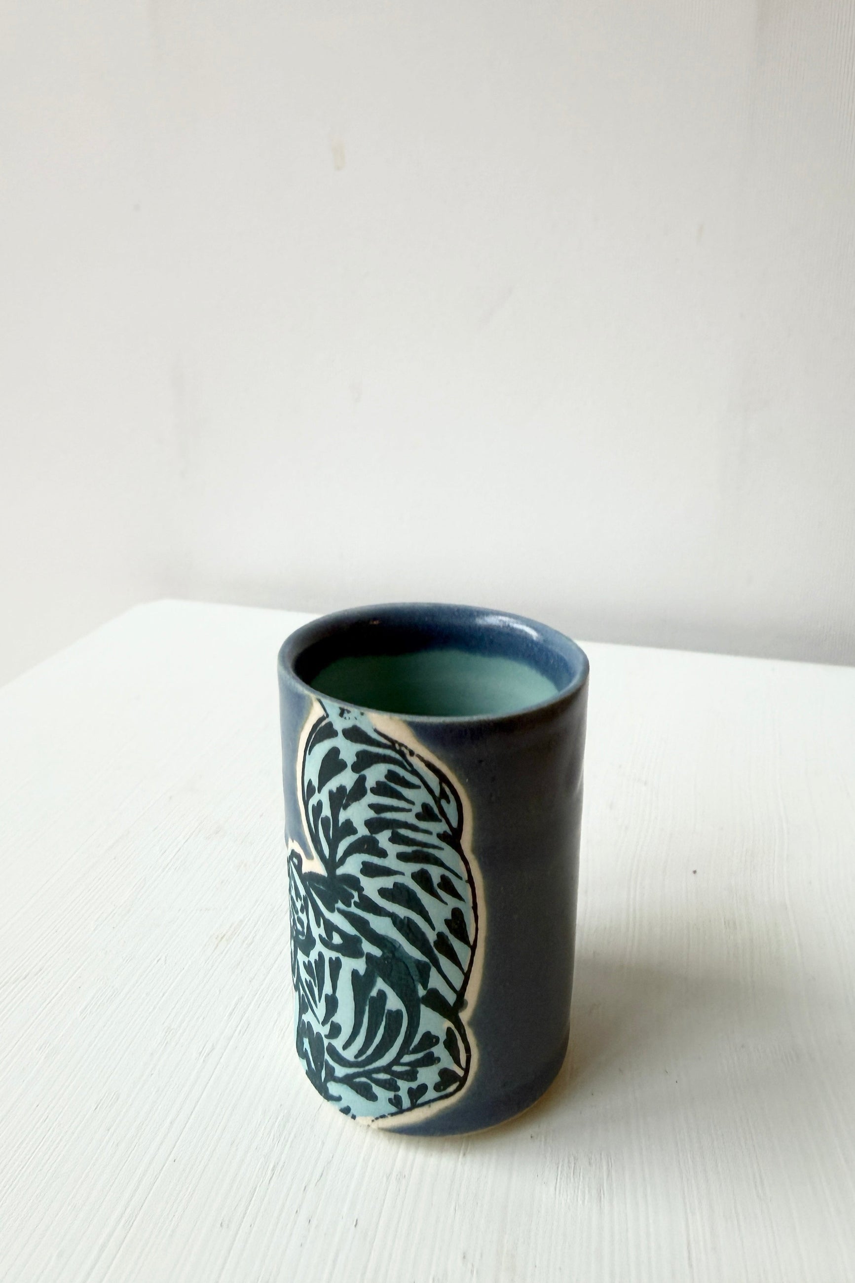 Ceramic cup with a decorative blue tiger by City in Bloom Ceramics on a white surface ©Sprout Home