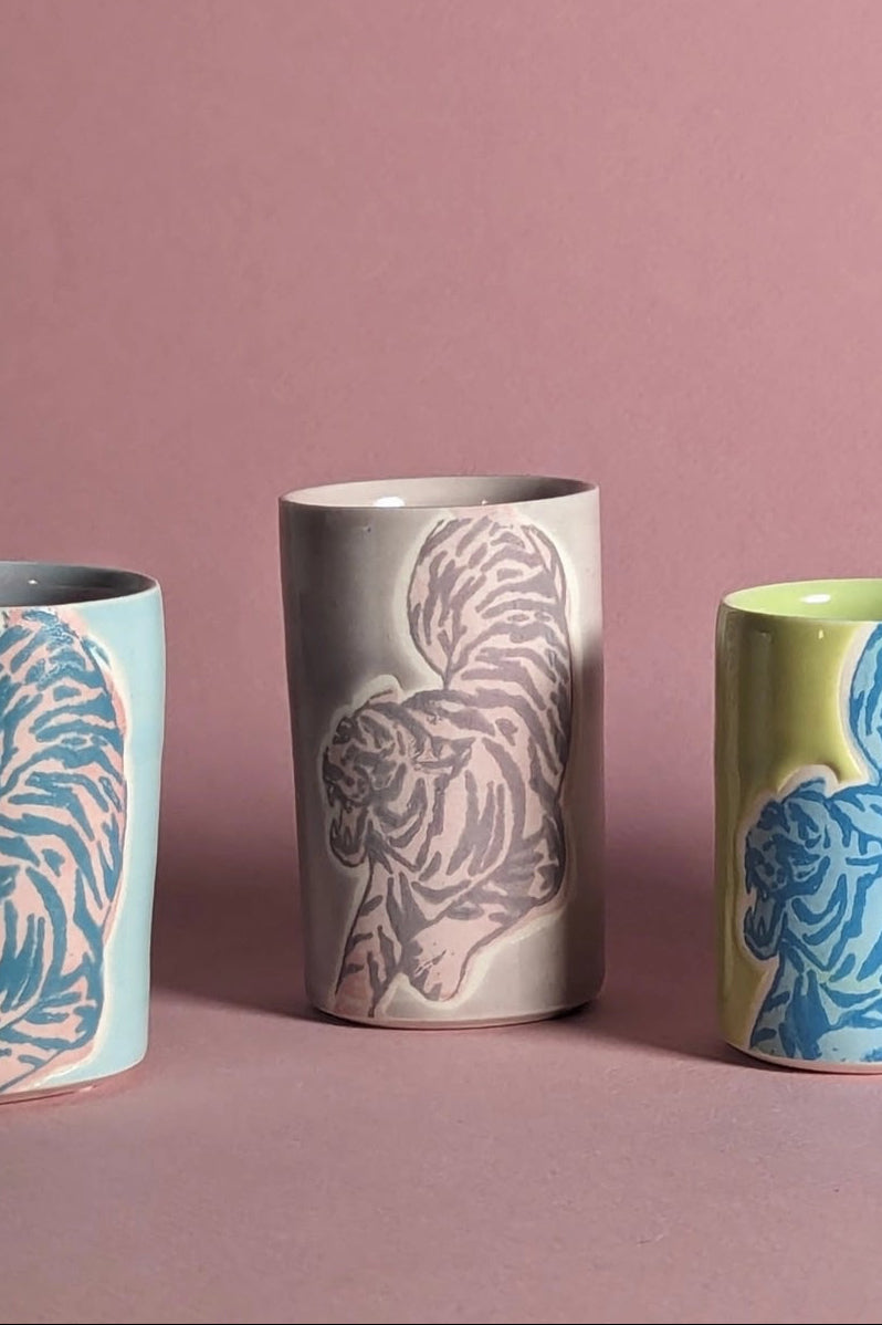 Ceramic cups with animal patterns on a pink background focusing on the mauve colored one in the center ©City in Bloom Ceramics