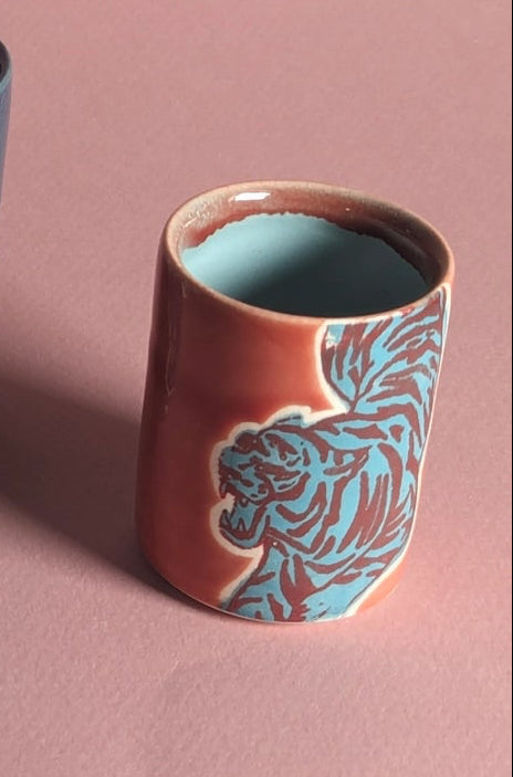 ceramic cup in a red teal with animal patterns on a pink background ©City In Bloom Ceramics