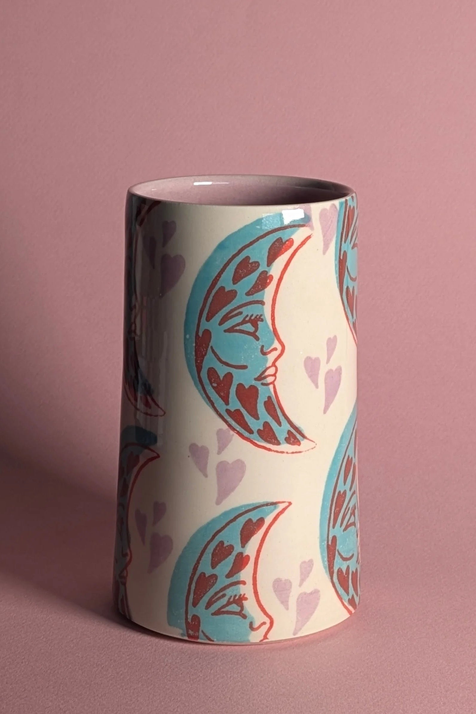 Cylindrical mug with decorative design on a pink background ©City in Bloom Ceramics