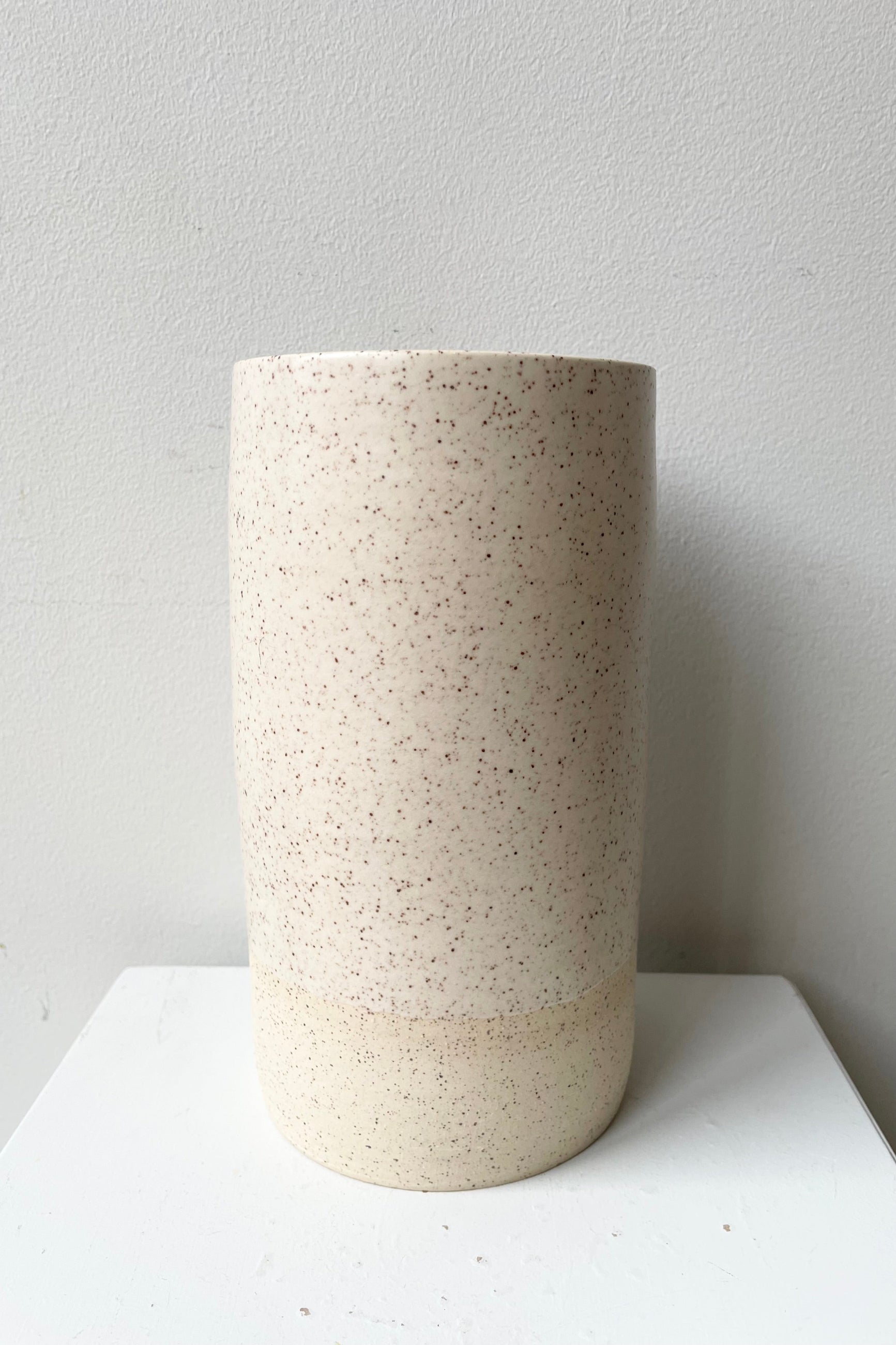 The Jaqueline vase in Cream Speckle large against a white wall at Sprout Home. ©Sprout Home