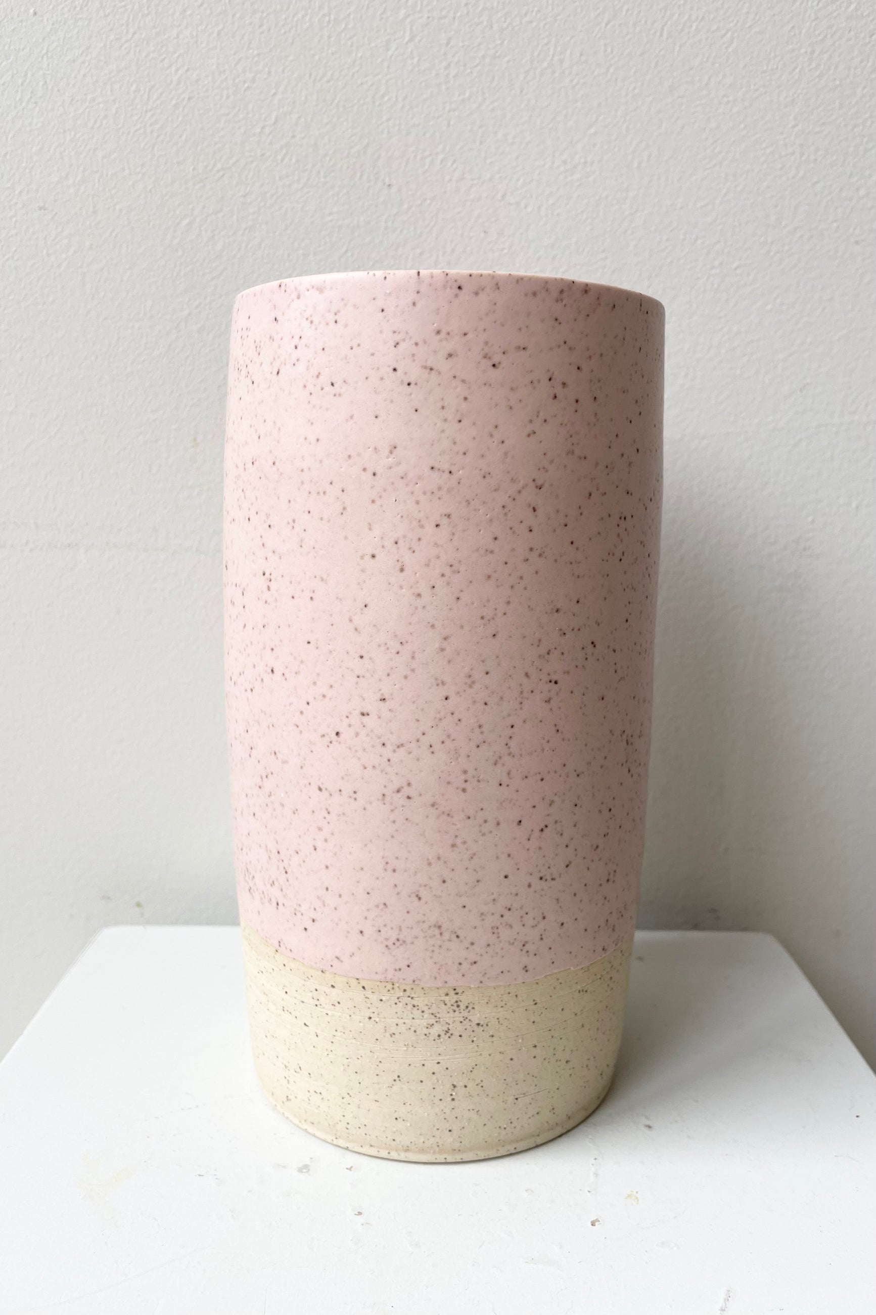 The Pink Speckle Jacqueline vase large against a white wall showing off its handmade shape and glaze. ©Sprout Home