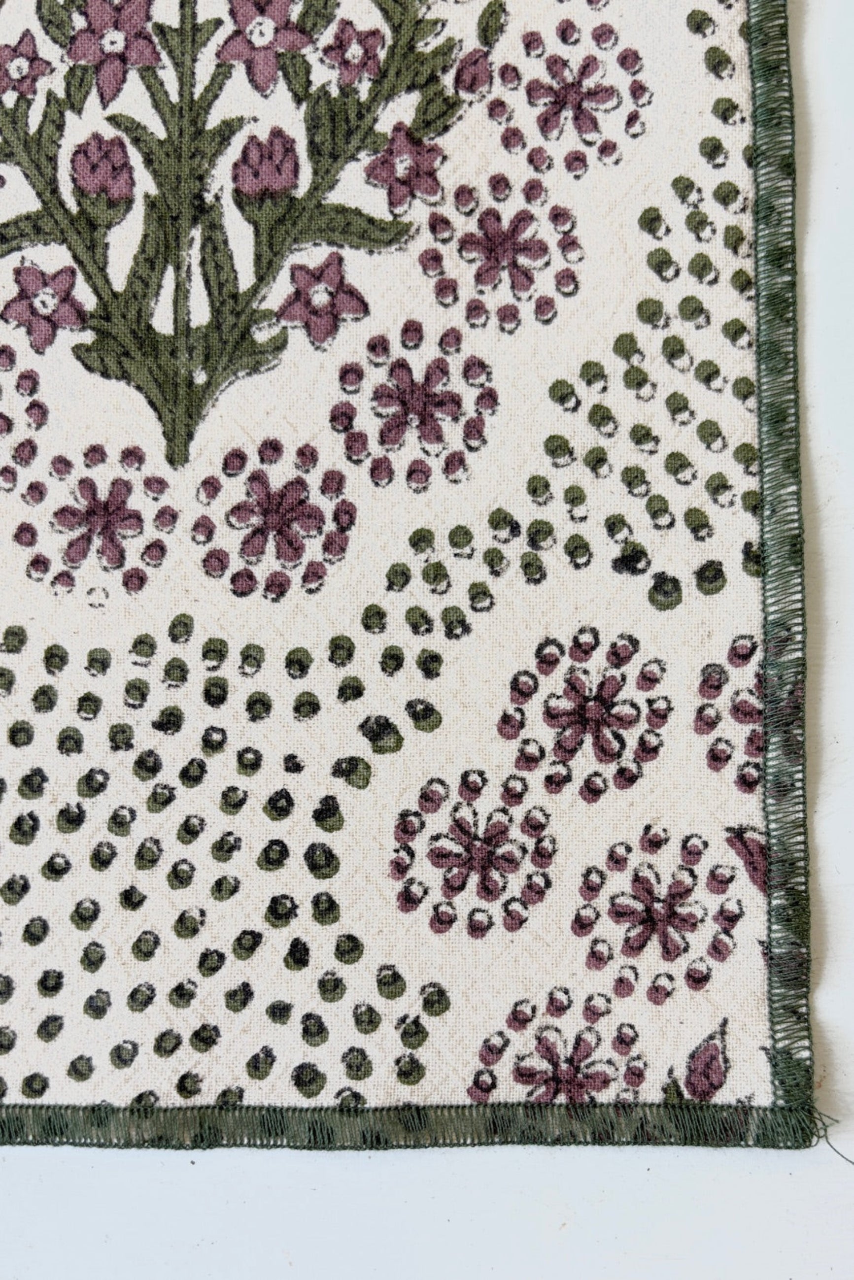 Finished edges of hand-block-printed napkin on Khadi cotton with a floral and dot pattern in olive and saffron color ©Sprout Home