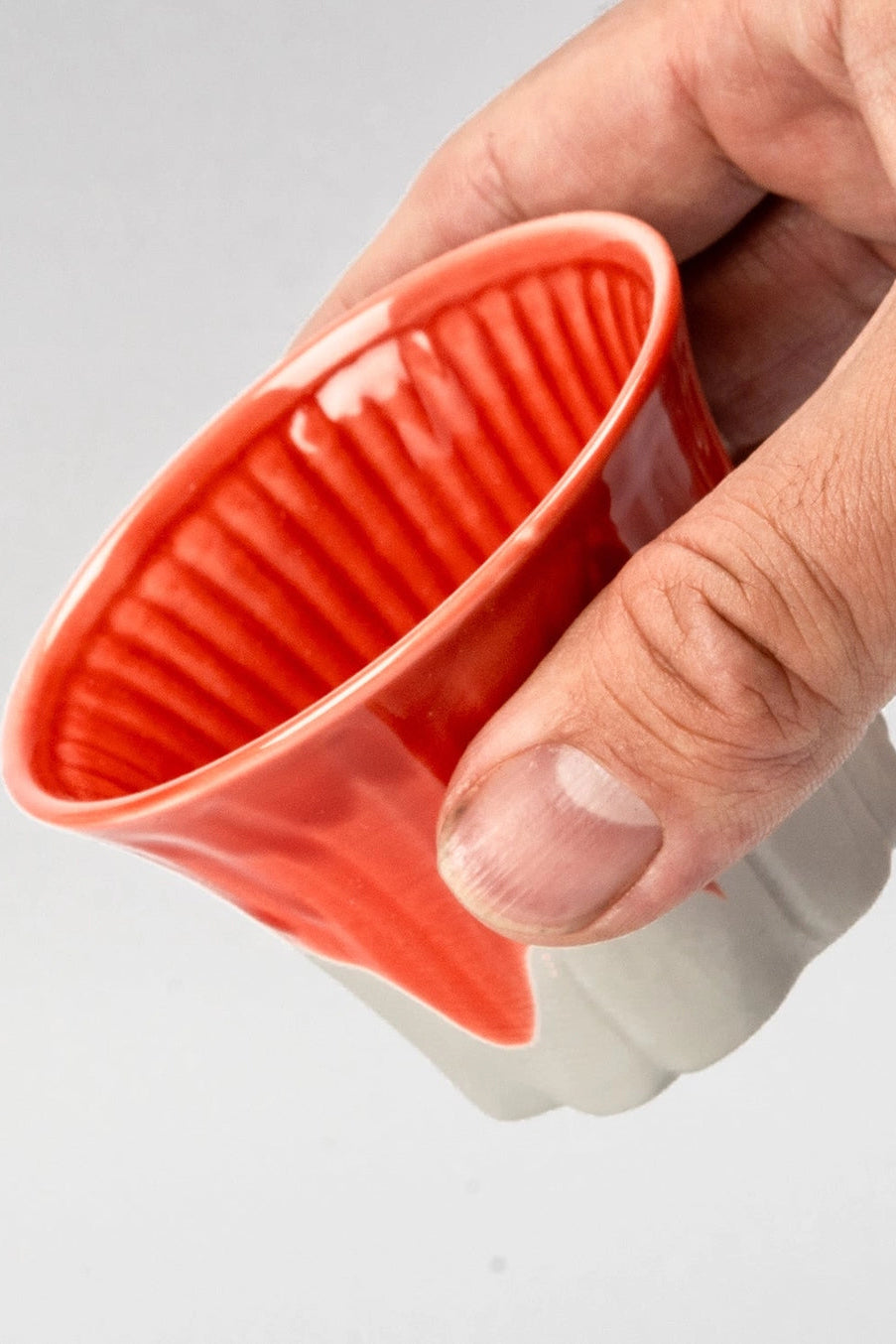 Hand holding a red Fuji Sakura cup against a gray background ©Urban Tokyo