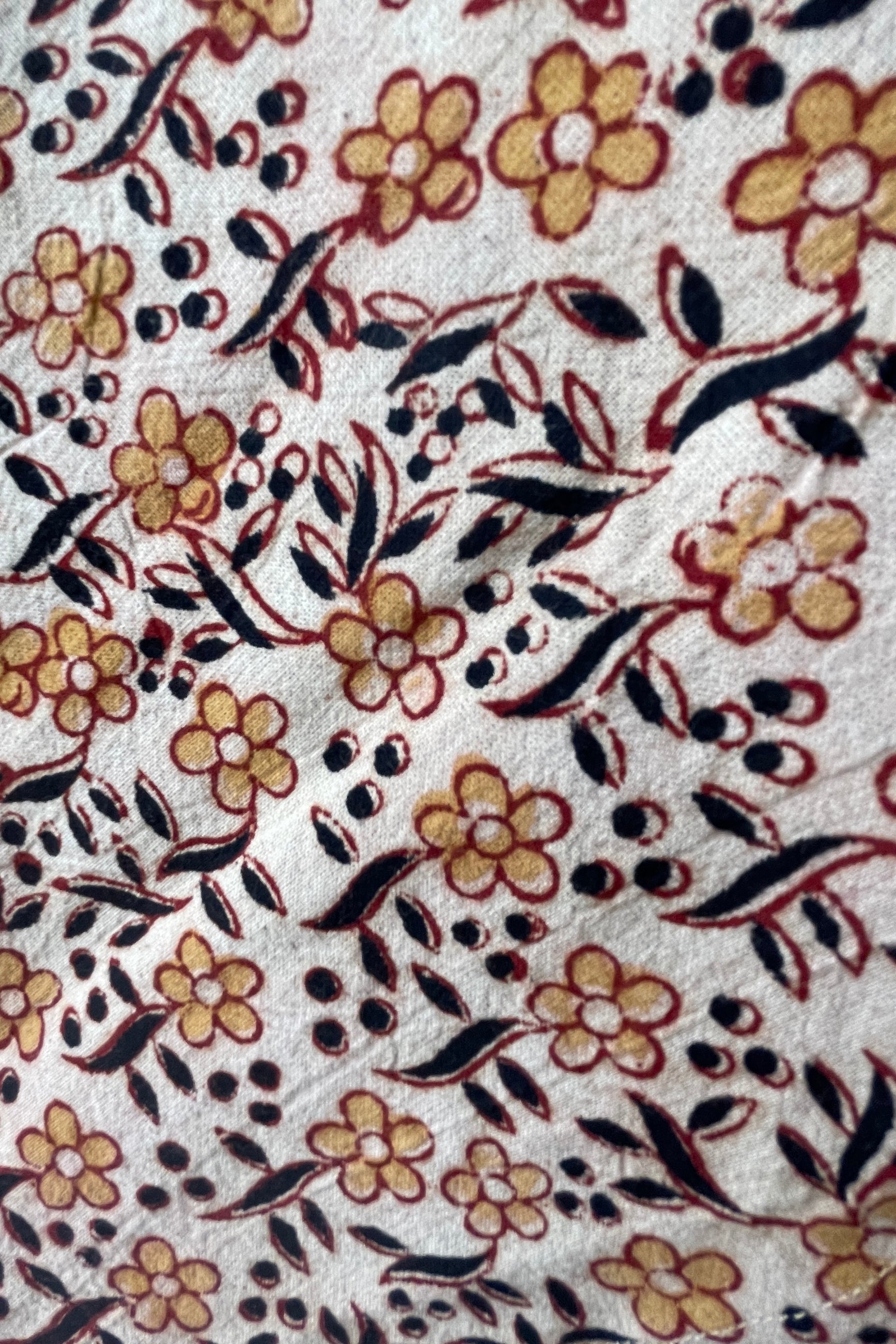 detail of the Sao napkin print showing the yellow and blue flowers with burgundy outlines on a neutral background. ©Sprout Home