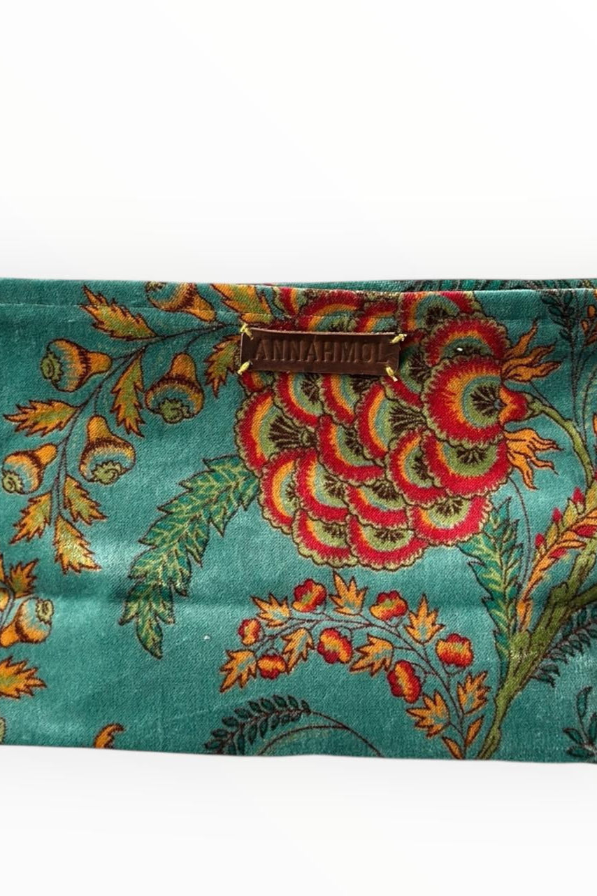 Floral teal and yellow patterned pouch with a brand name on a white background ©Annahmol
