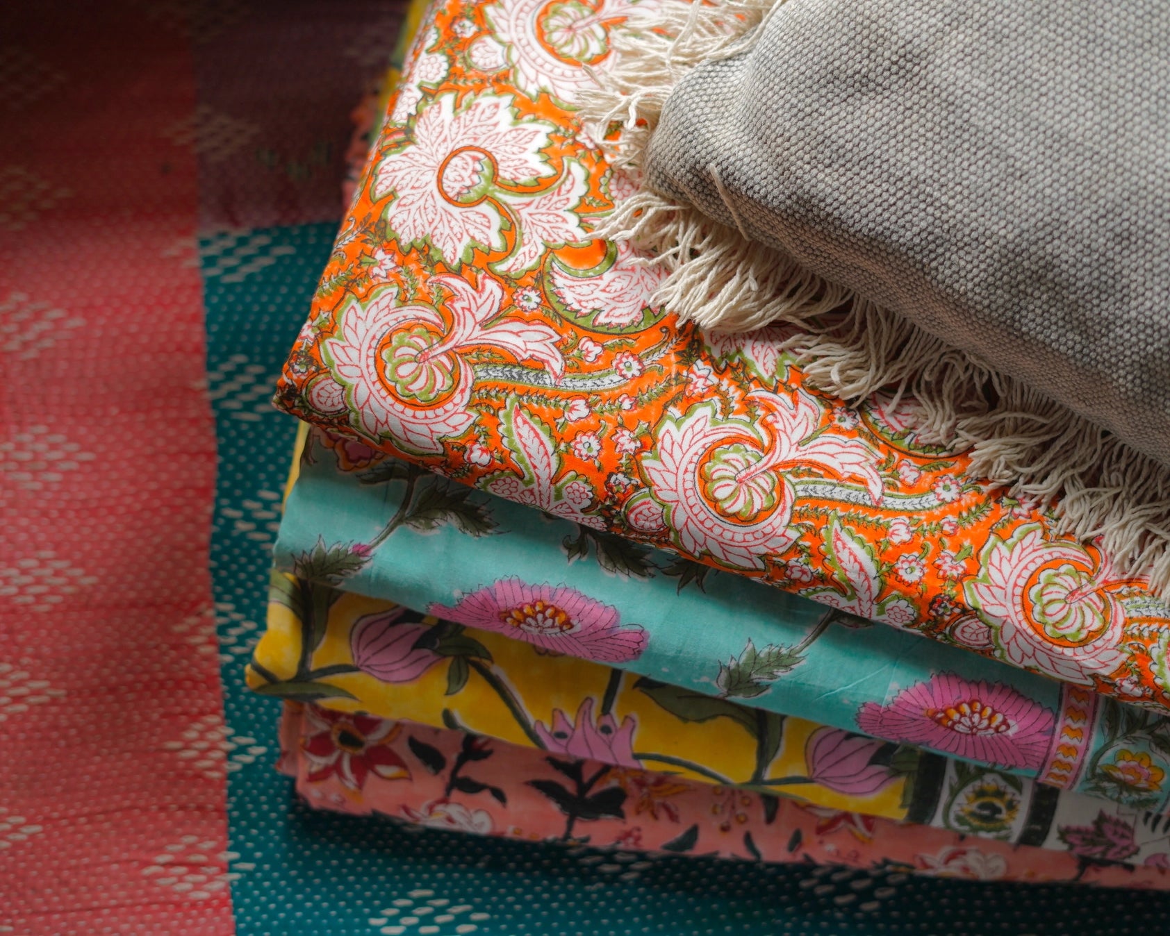 Stack of Block Print Reversible Summer Cotton Blanket colorful folded fabrics with floral patterns on a light background ©Annahmol