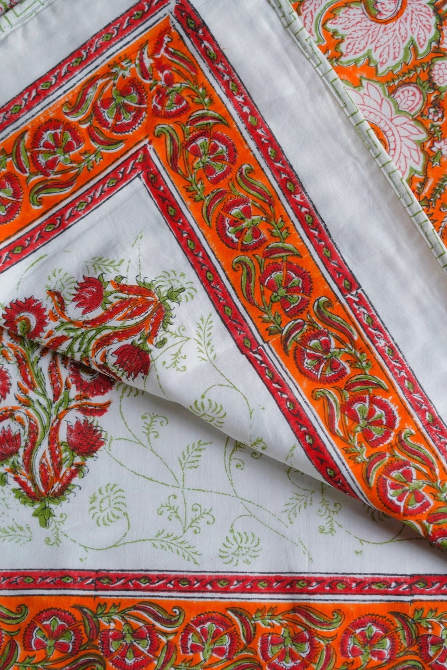 Colorful fabric with intricate orange and cream patterns and designs on a reversible blanket ©Annahmol