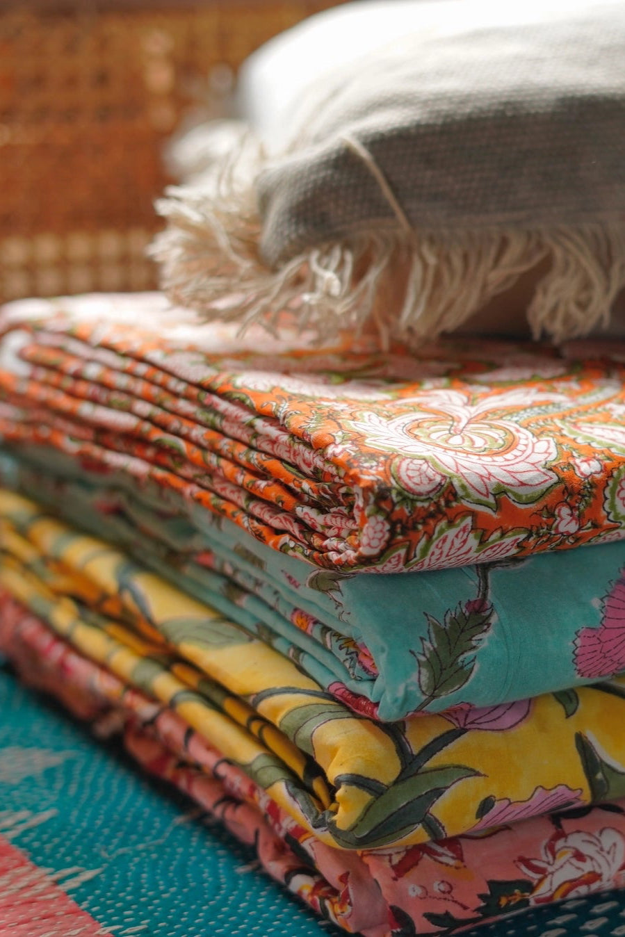 Stack of Block Print Reversible Summer Cotton Blanket colorful folded fabrics with floral patterns on a light background ©Annahmol